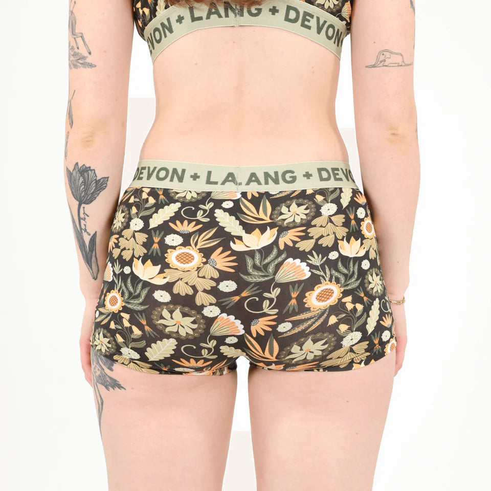 A person wearing floral boyshort underwear against a white background