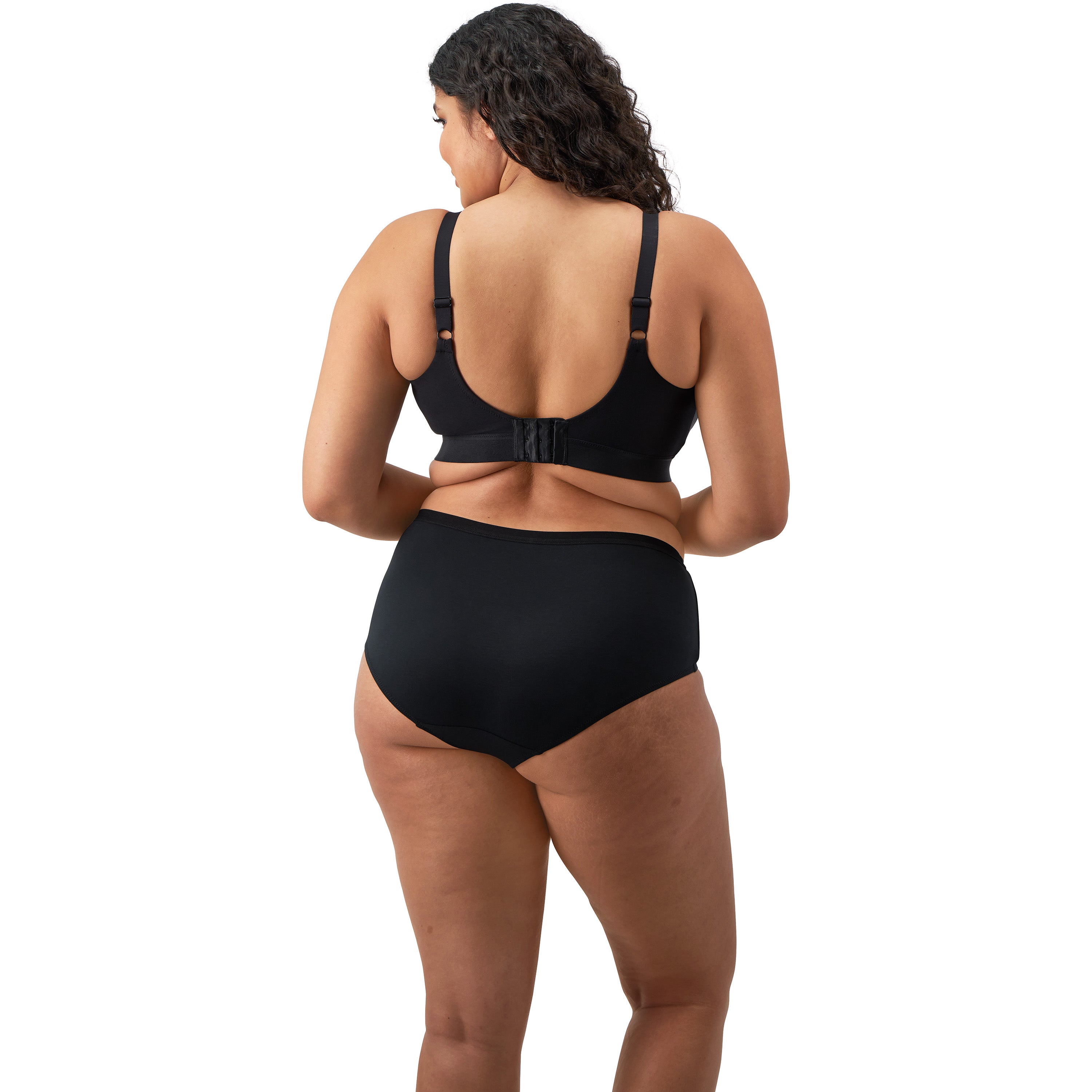 A woman wearing a black bra and panty set against a white back ground.