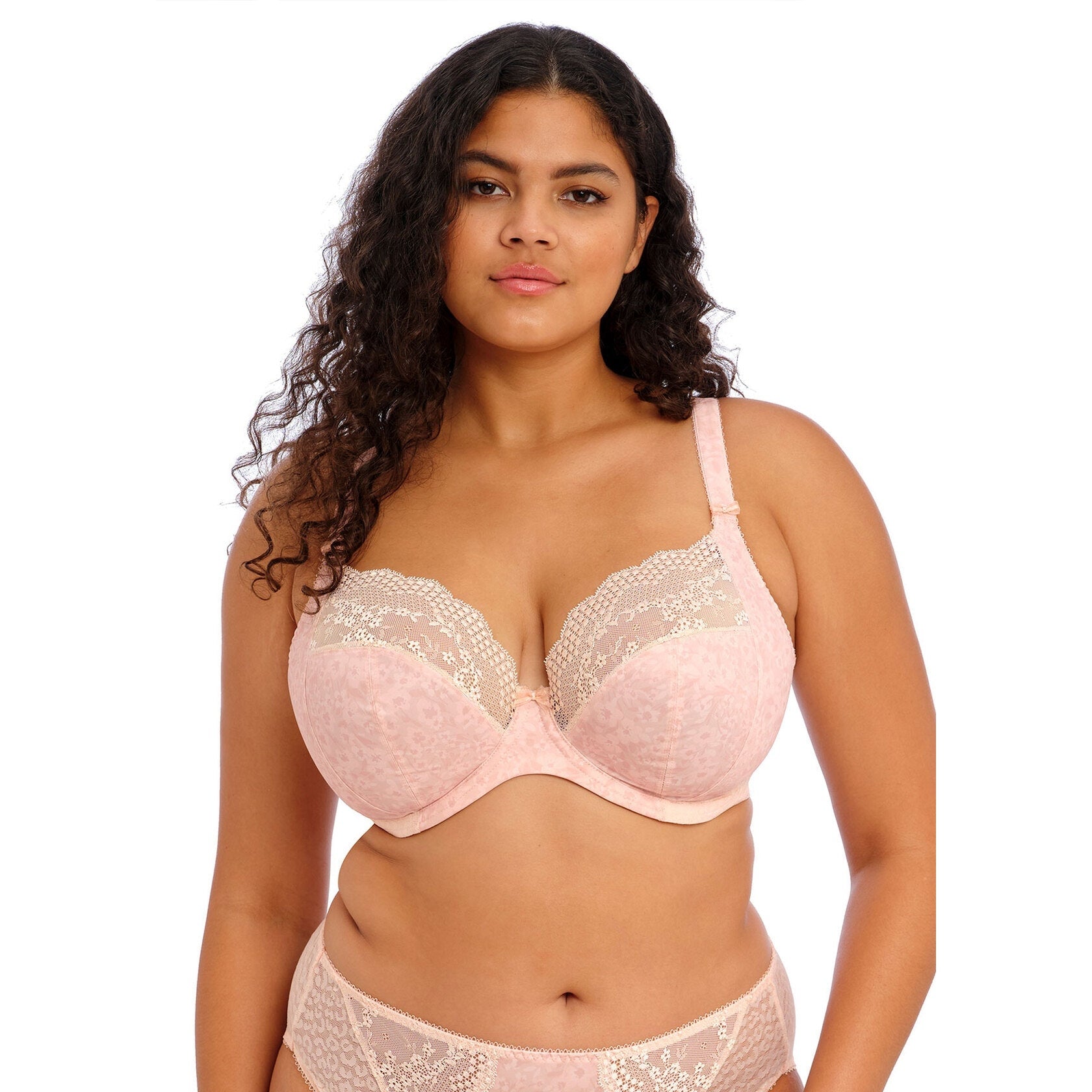 A woman wearing a pink floral and lace bra and panty set against a white back ground.