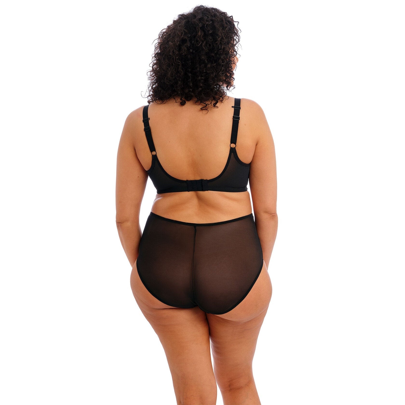 A person wearing a black bra and panty set against a white background.