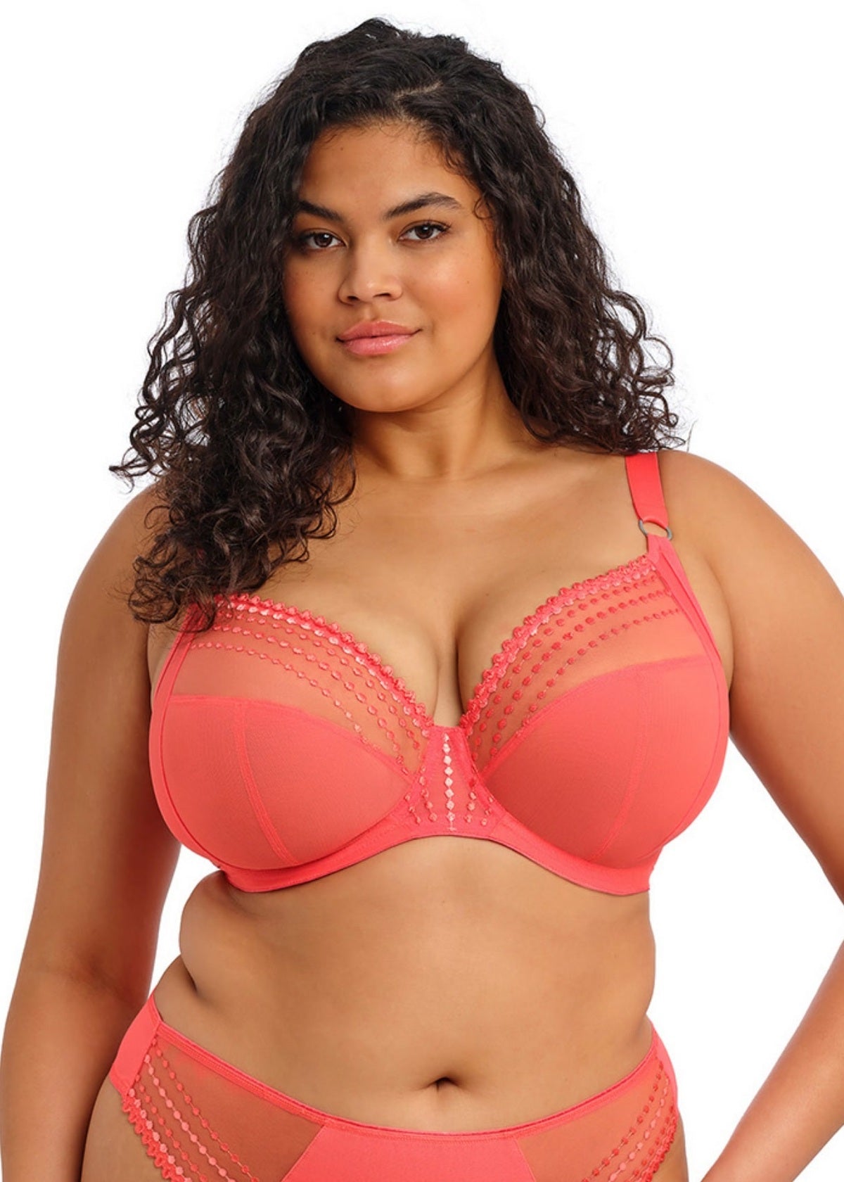 Woman wearing a coral bra and panties set on a white background