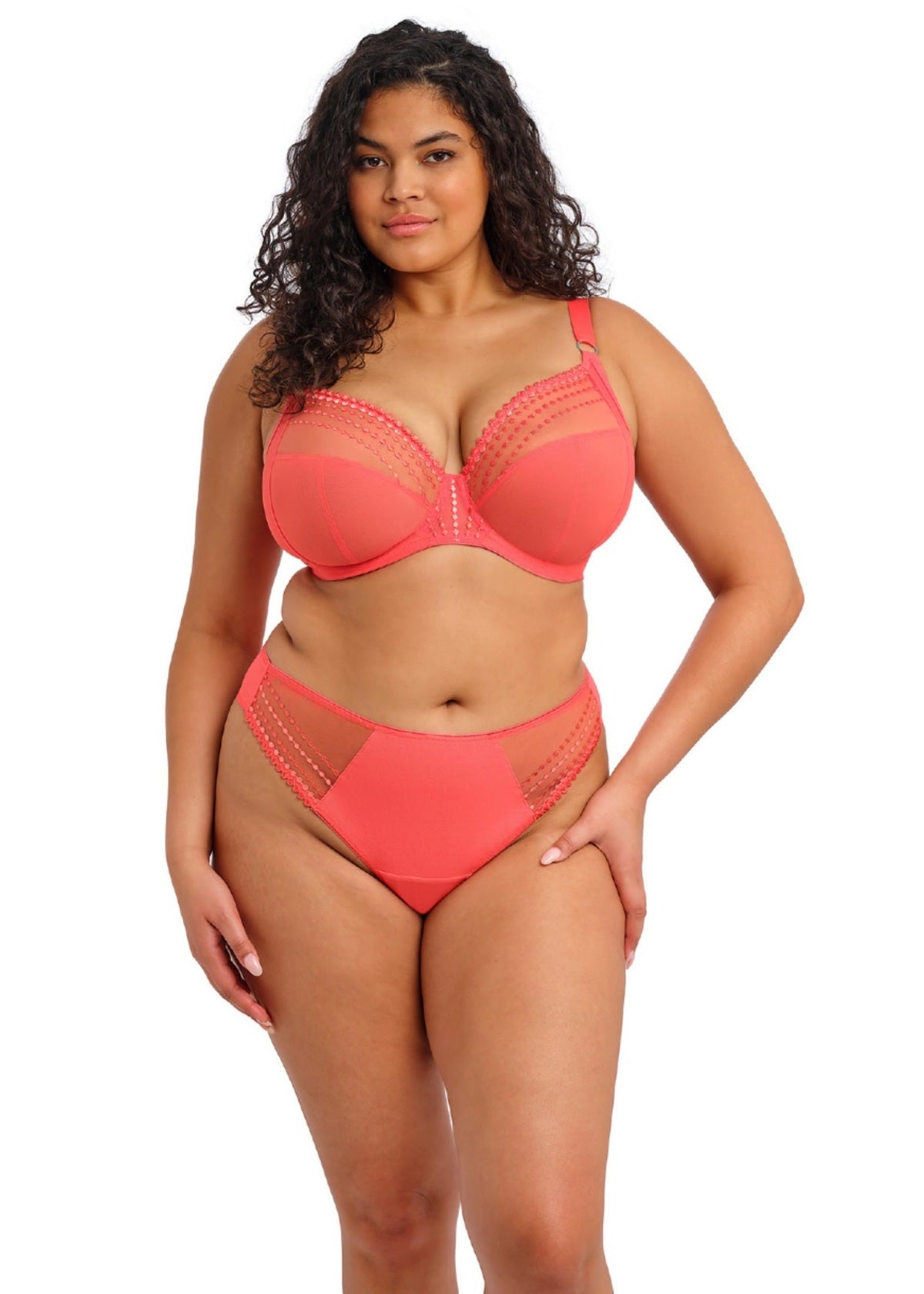 Woman wearing a coral bra and panty set on a white background