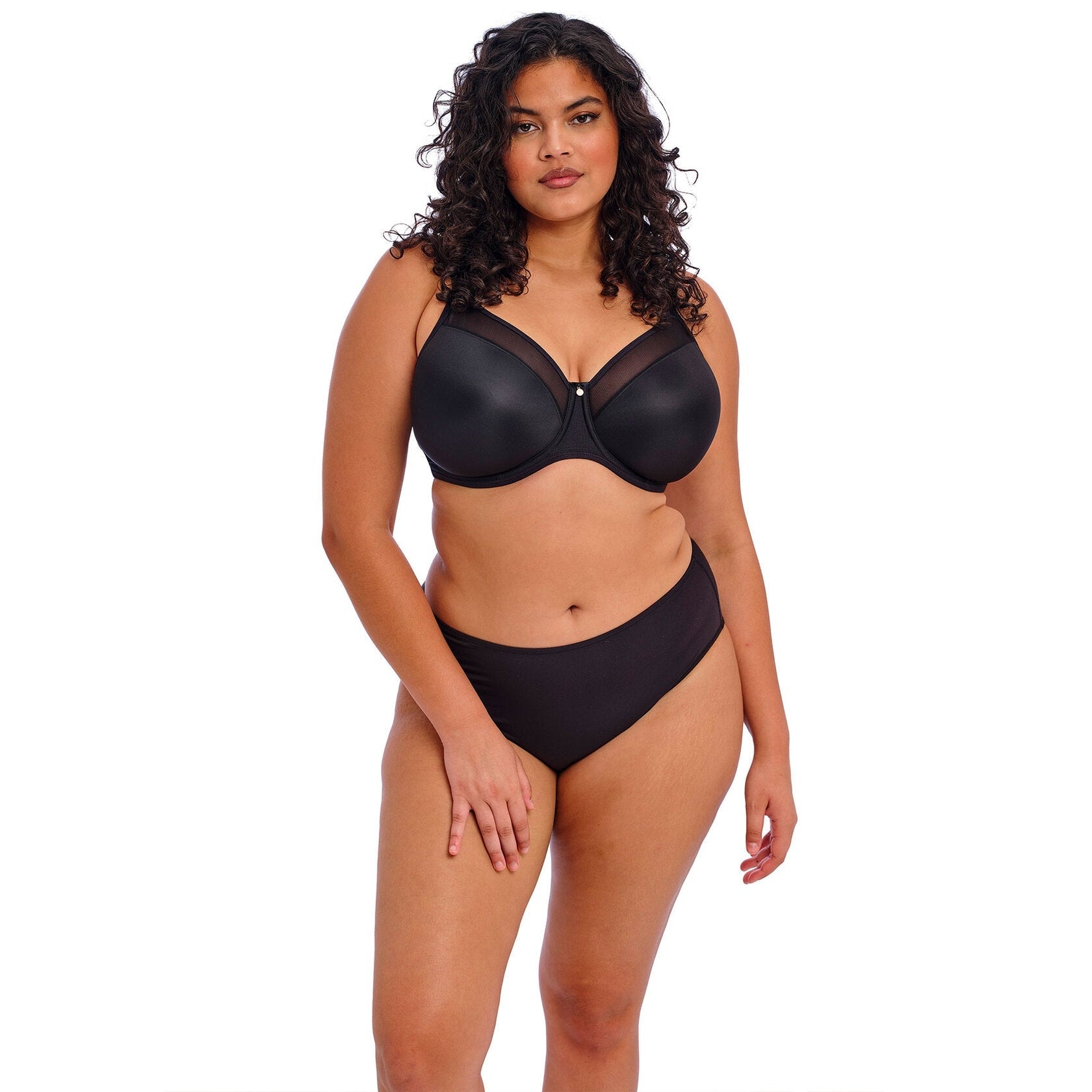 A woman wearing a black bra and panty set against a white back ground.