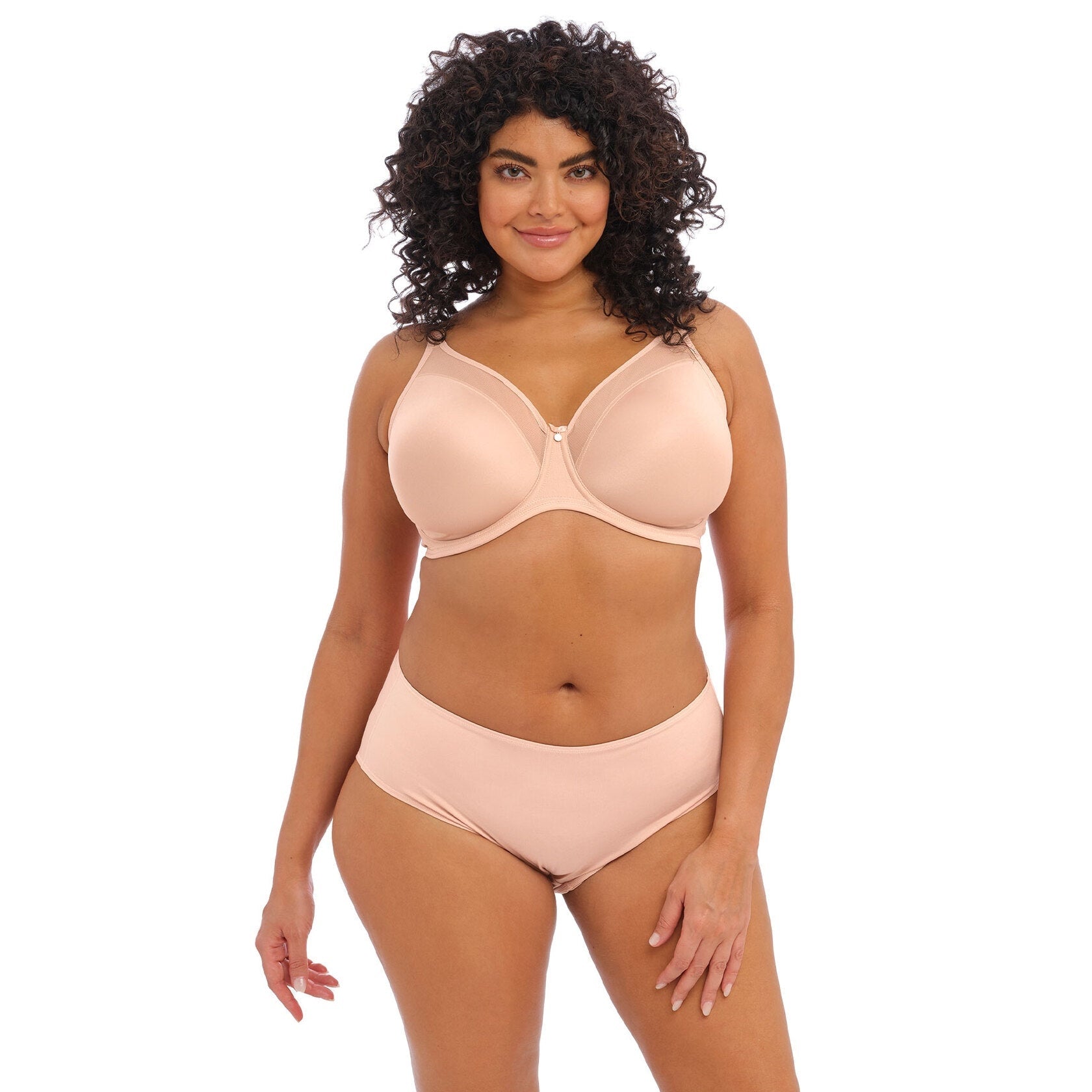 Woman wearing a beige bra and panty set against a white back ground.