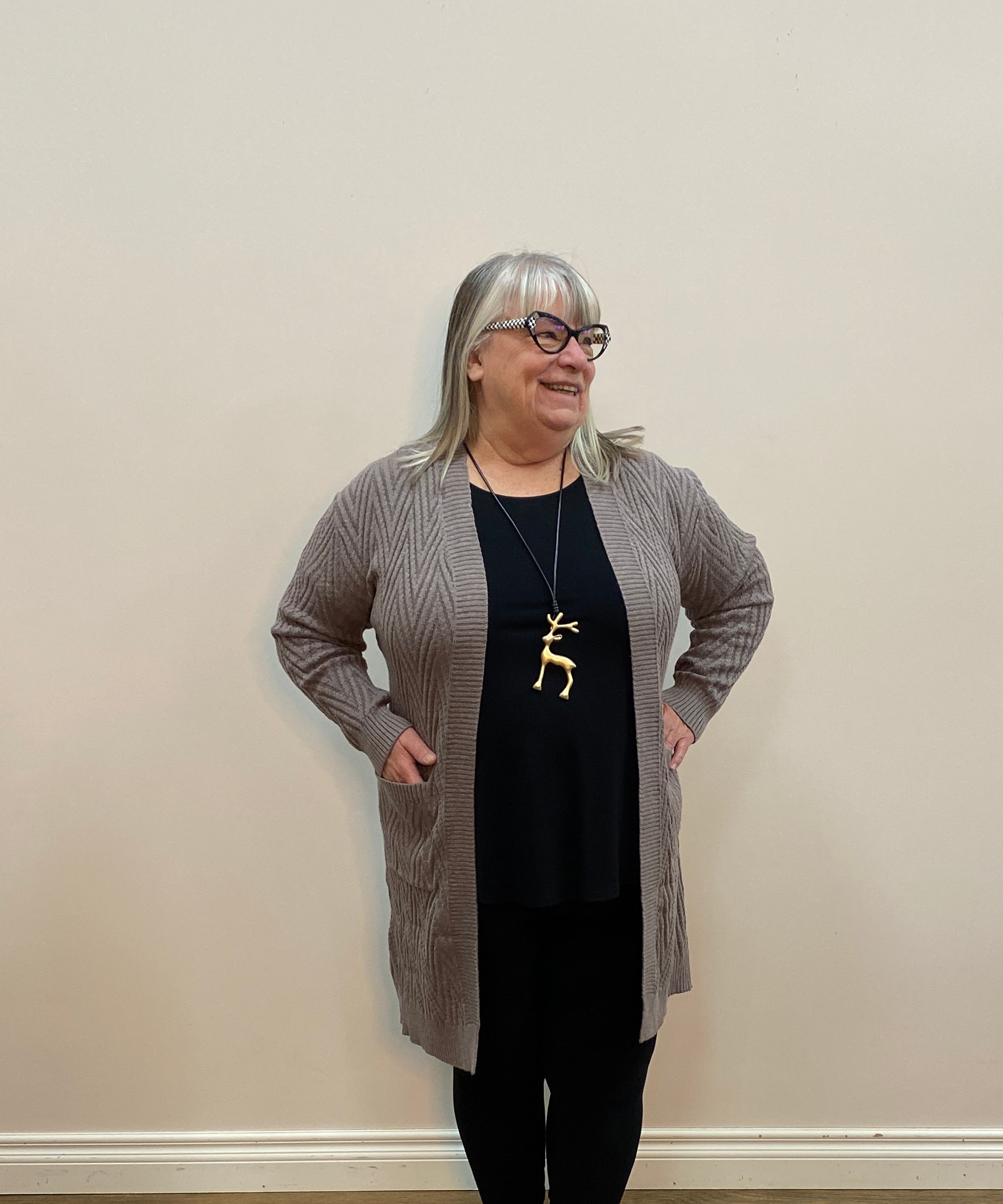 Person standing in a room with wooden flooring and a white wall.