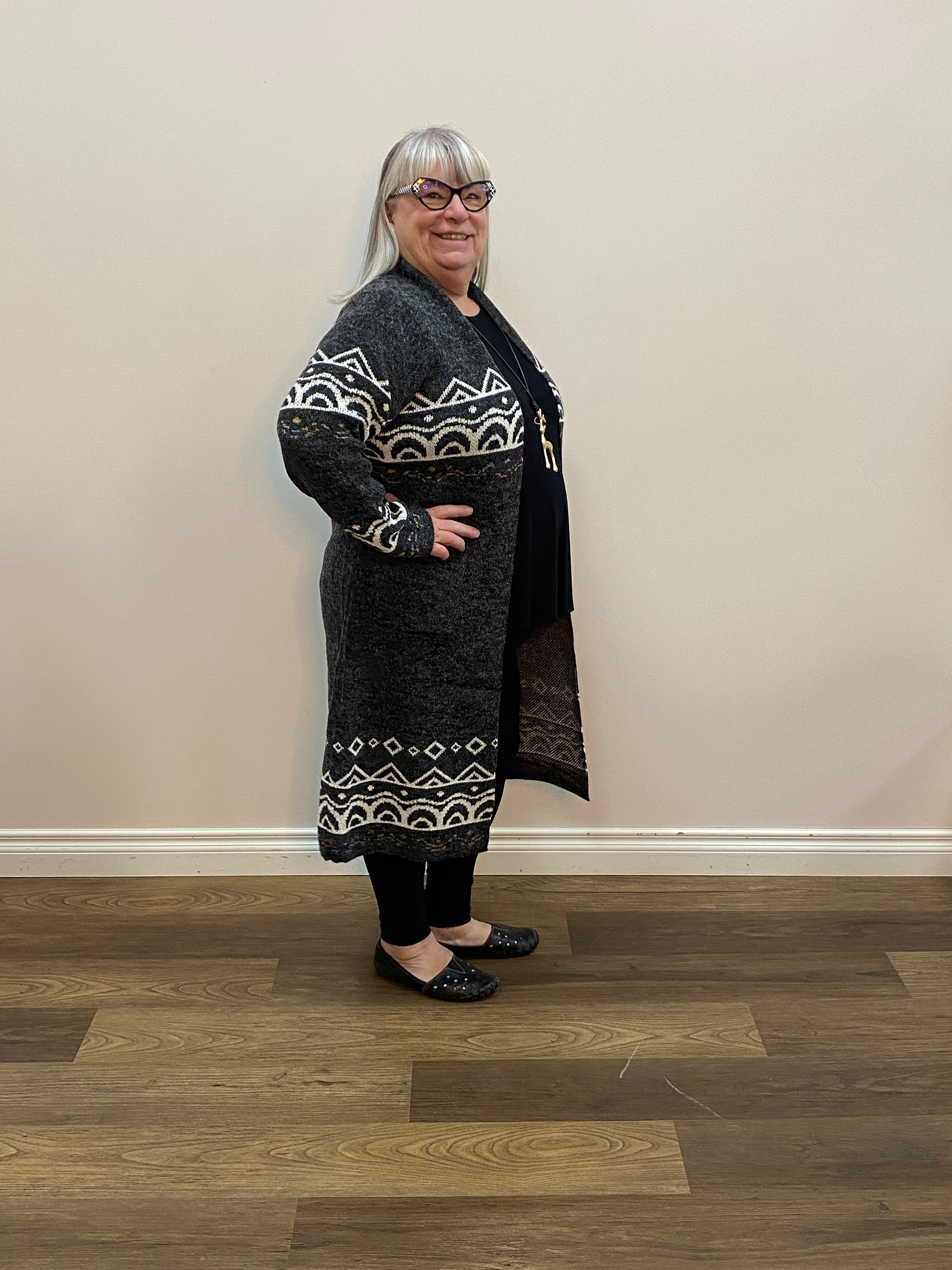 Person wearing a black outfit with white patterns standing on a wooden floor.