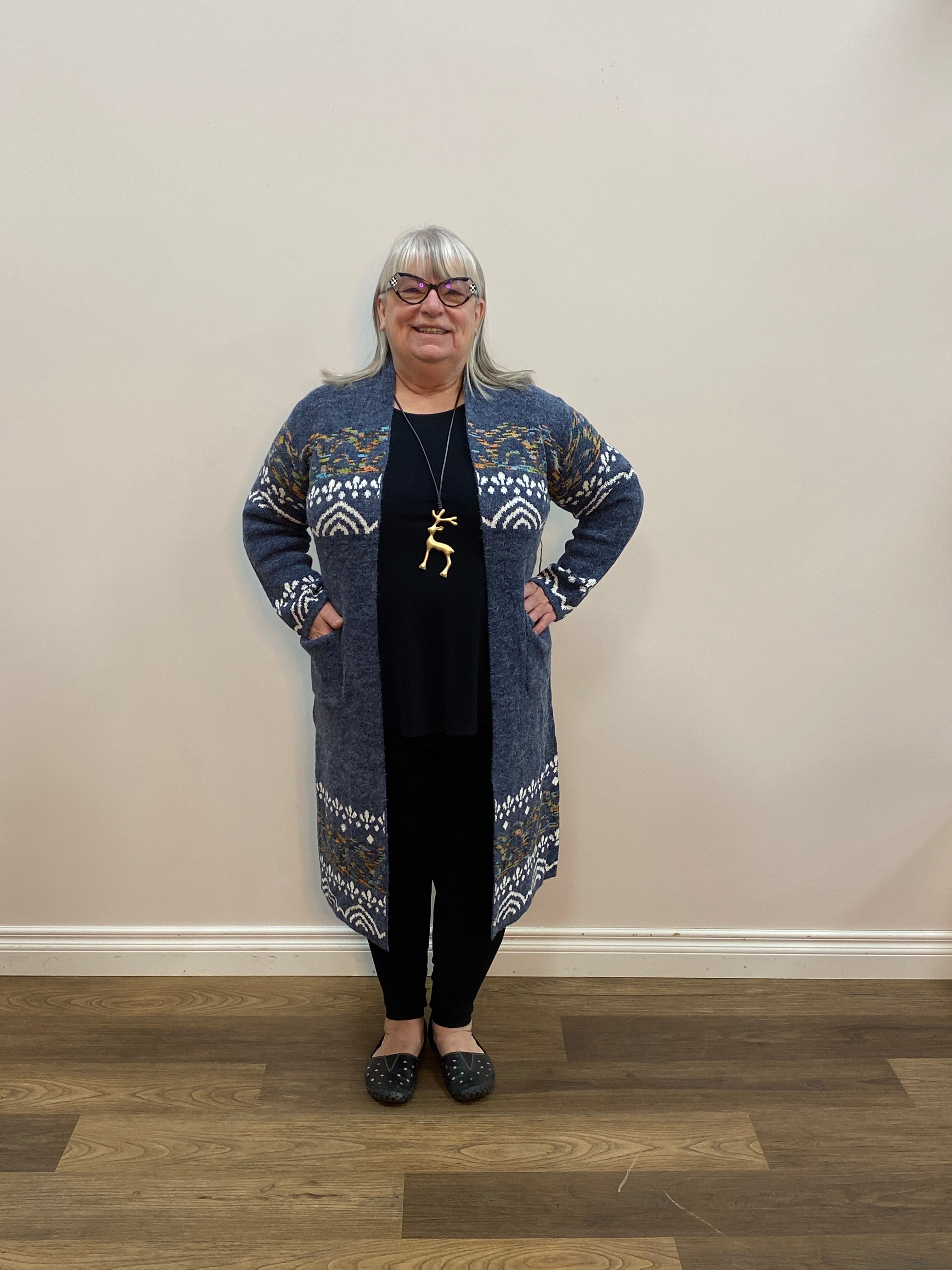 Person wearing a patterned outfit standing in a room with wooden flooring.
