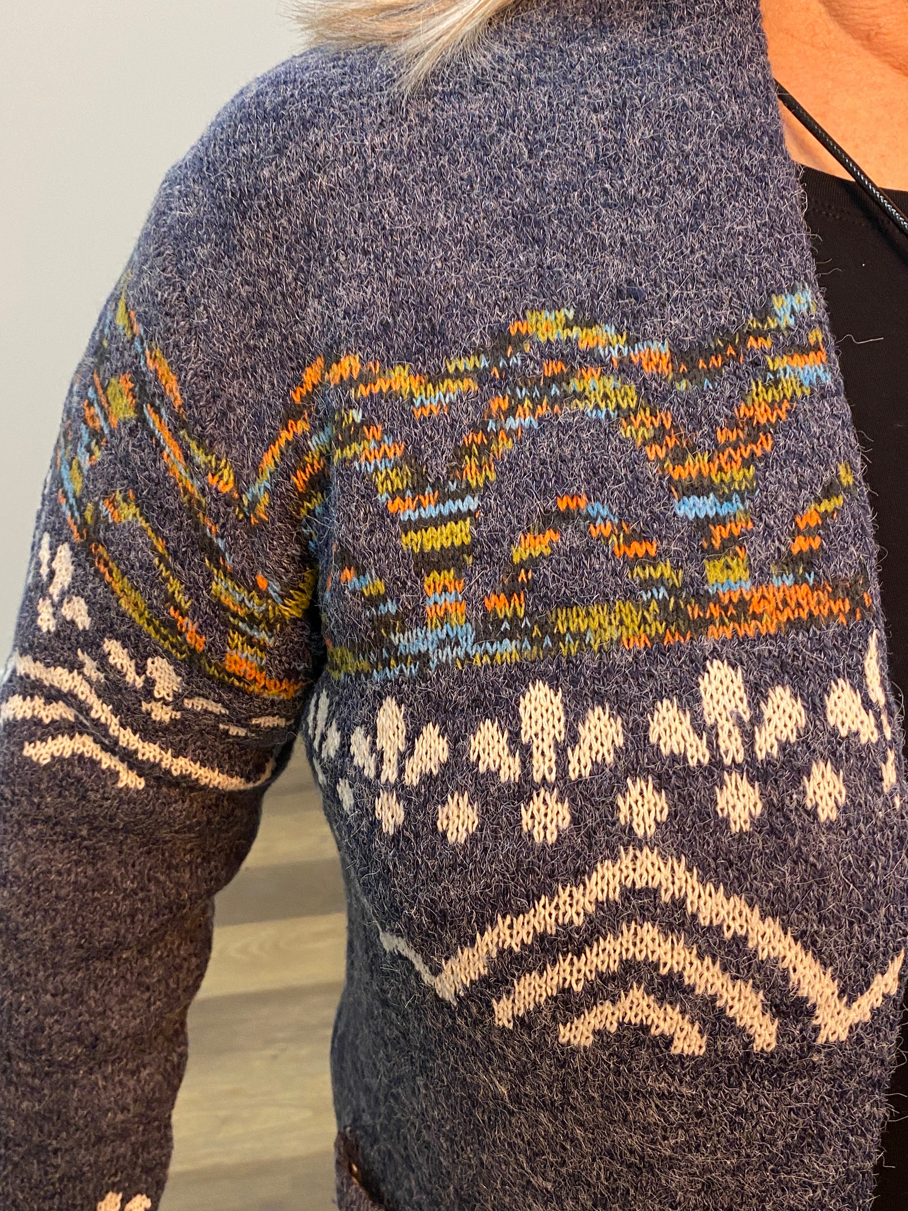 Close-up of a patterned sweater with blue, orange, and white colors.