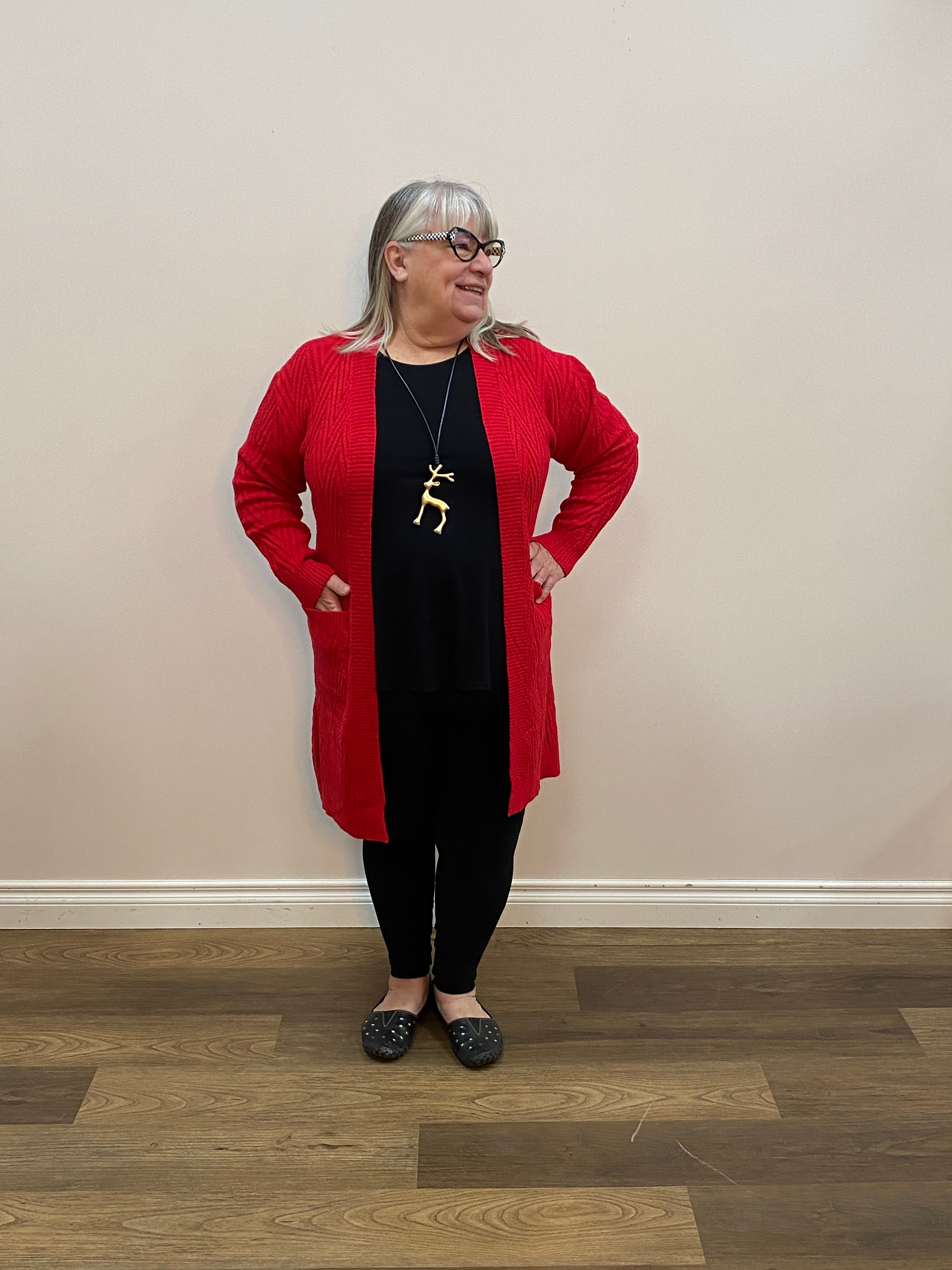 Person wearing a red and black outfit with a gold necklace on a wooden floor.