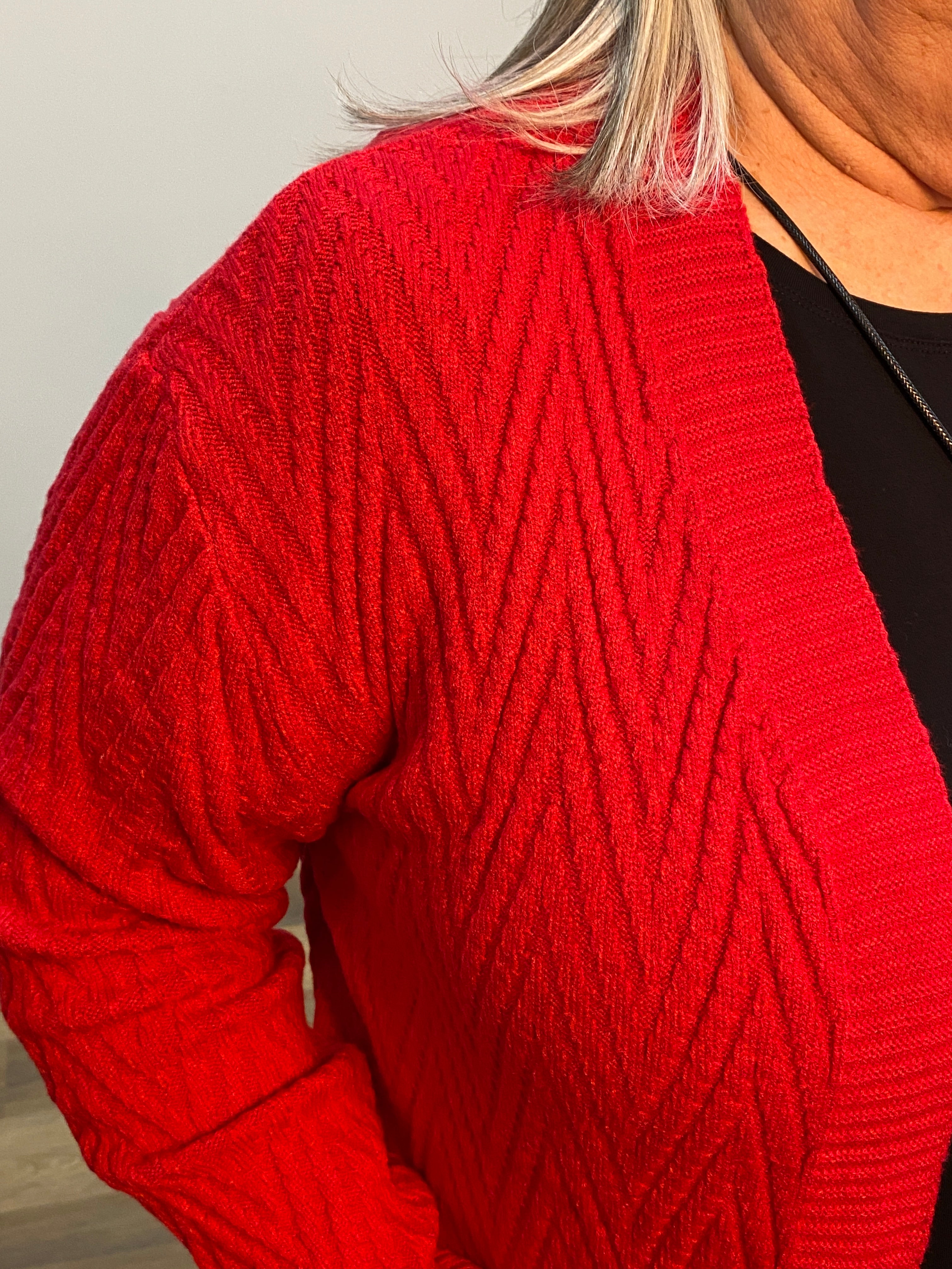 Close-up of a red knitted sweater sleeve on a neutral background