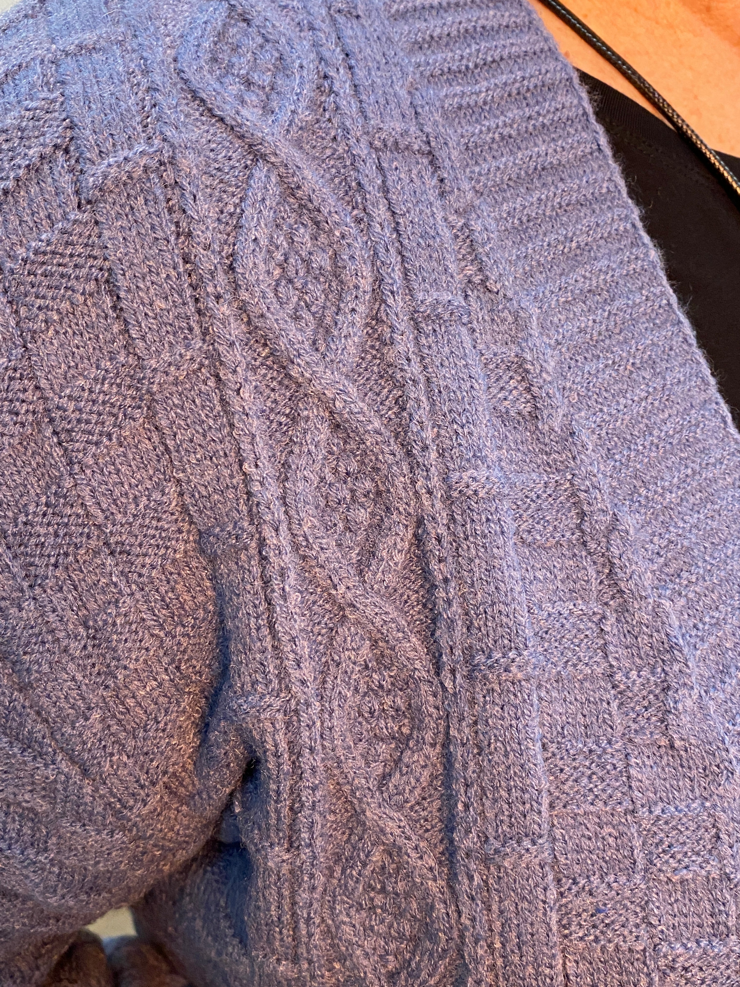 Close-up of a textured blue sweater with cable knit pattern