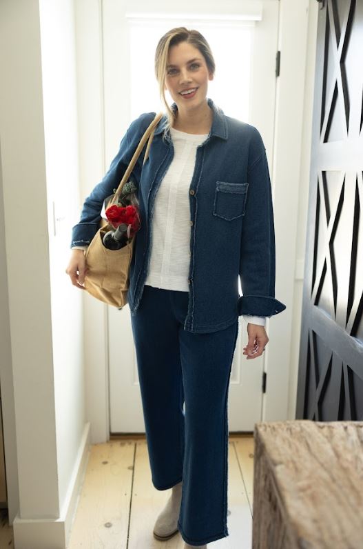 Woman in a blue outfit holding a bag with flowers indoors.