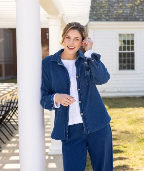 Woman wearing a blue denim jacket and pants standing outdoors.