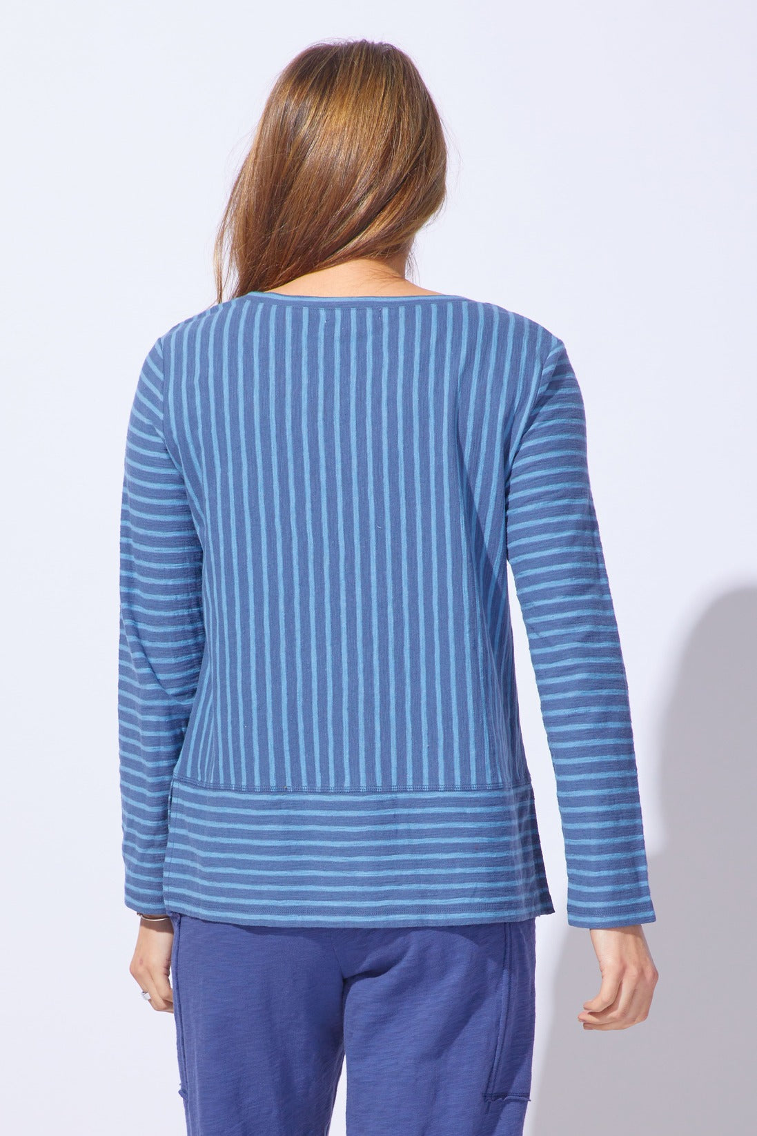 Person wearing a blue striped long-sleeve top and pants on a white background