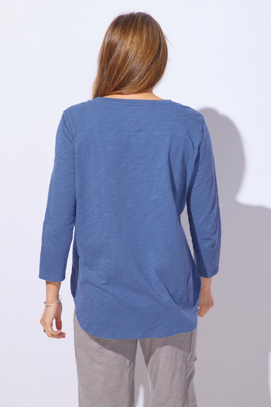Person wearing a blue long-sleeve top against a white background