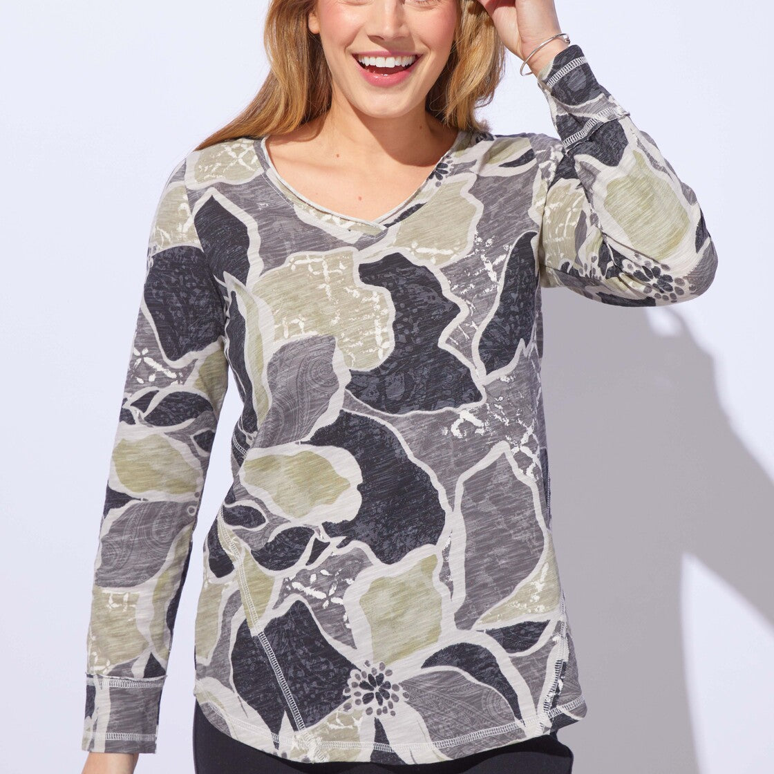 Woman wearing a floral patterned long-sleeve top against a white background