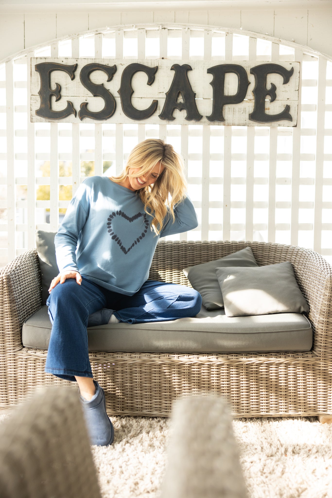 Woman sitting on a wicker chair with 'ESCAPE' sign above her