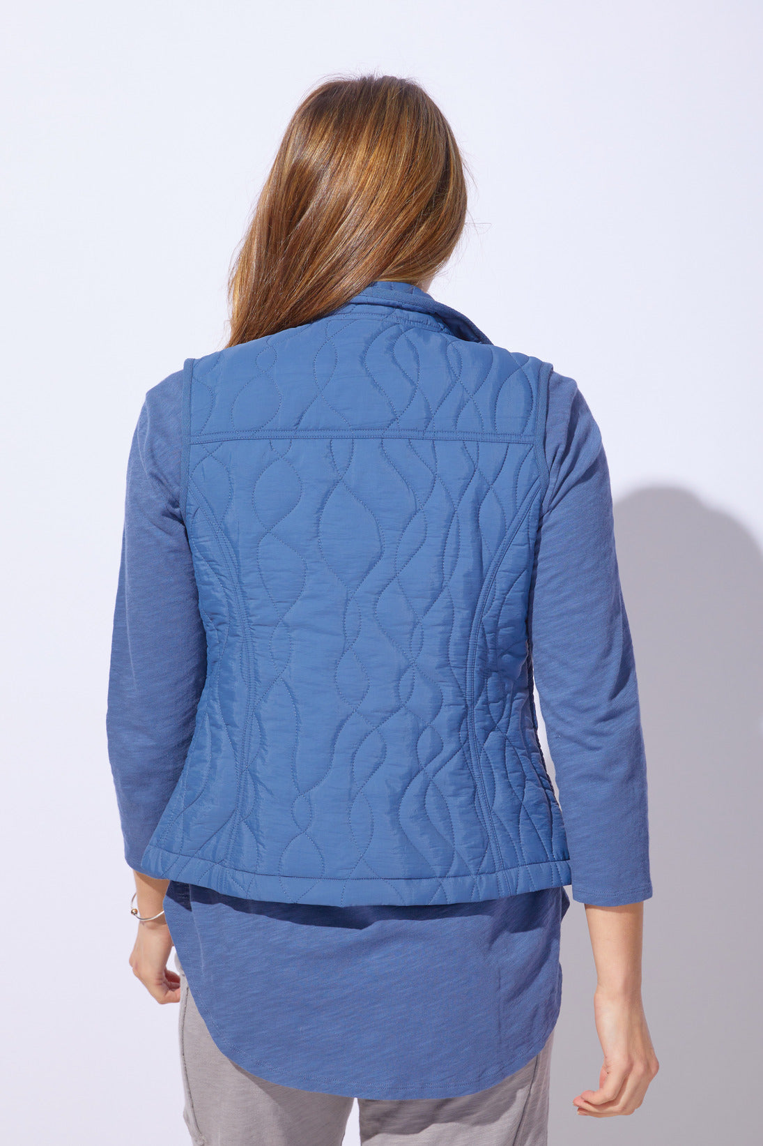 Person wearing a blue quilted jacket on a white background