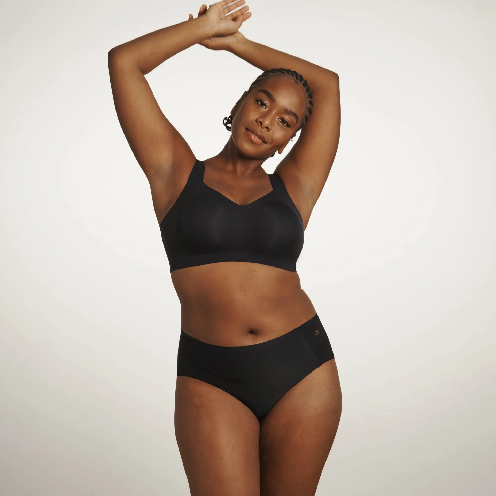 The Beyond Bra in Black, a wirefree bra shown on a model wearing a matching panty from the front view.