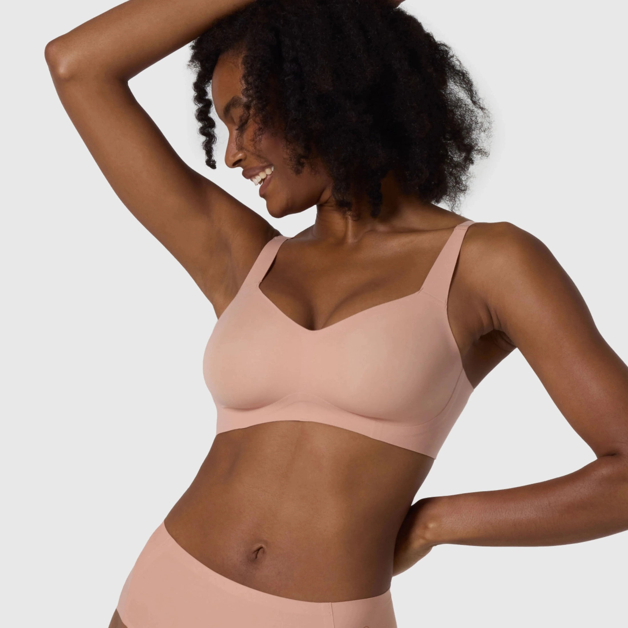 The Beyond Bra in Himalayan Salt, light pink neutral coloured wirefree bra shown on a model with her arms up to see the sides.