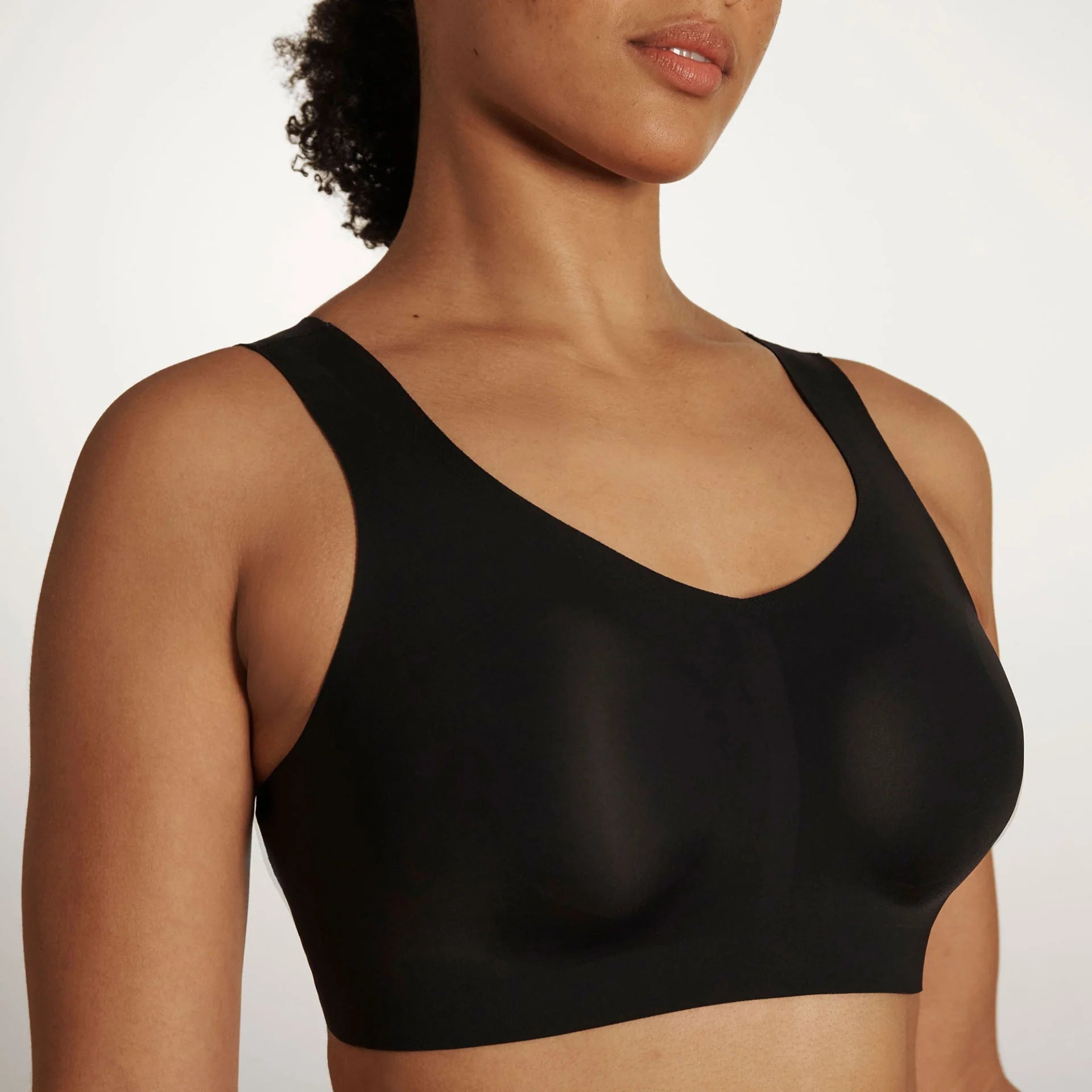 Woman wearing the Evelyn & Bobbie Defy Bra in Black, no wire pullover bra, against a white background, front view.