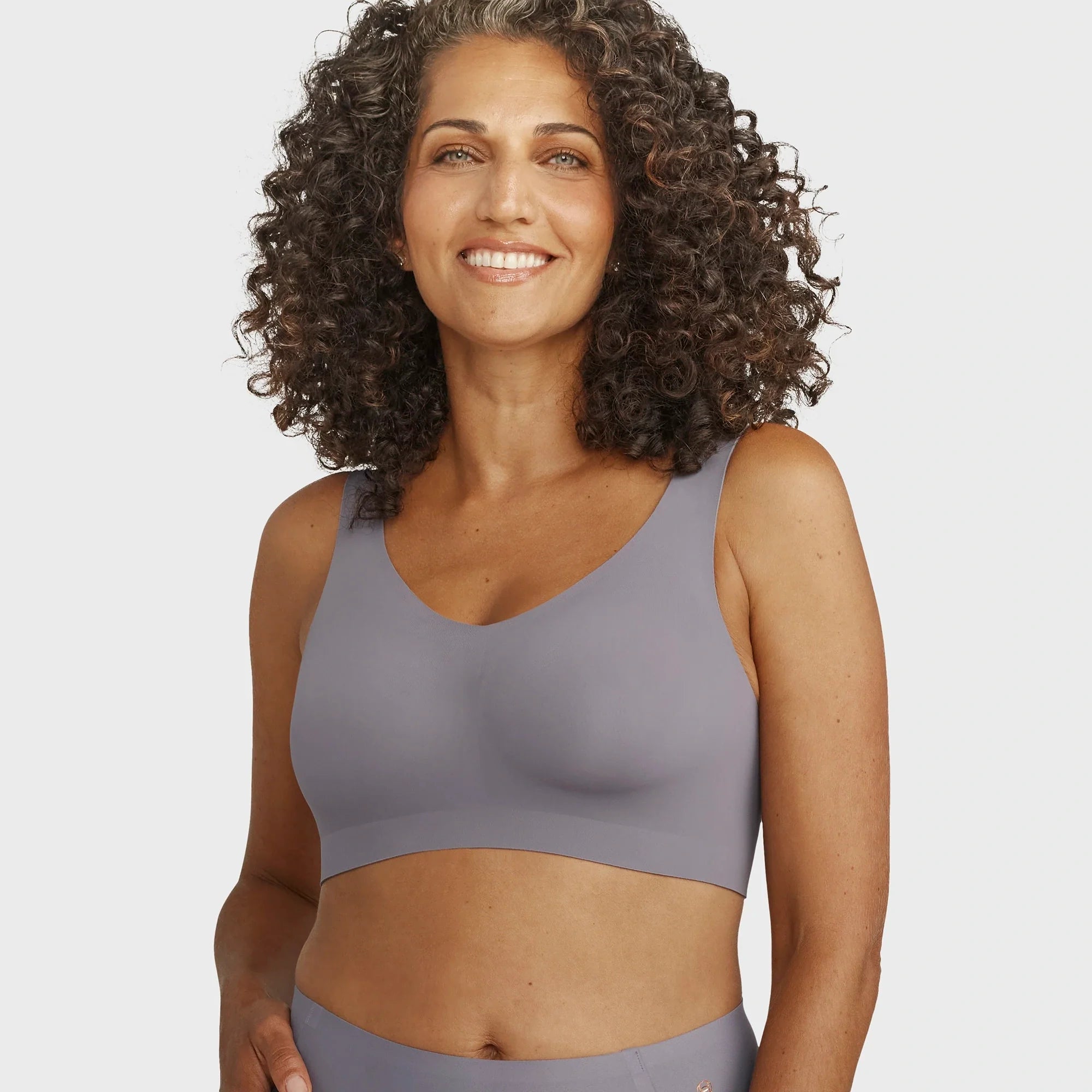 Woman wearing the Evelyn Bobbie Defy Bra in London Fog, light grey no wire bra, on a white background.