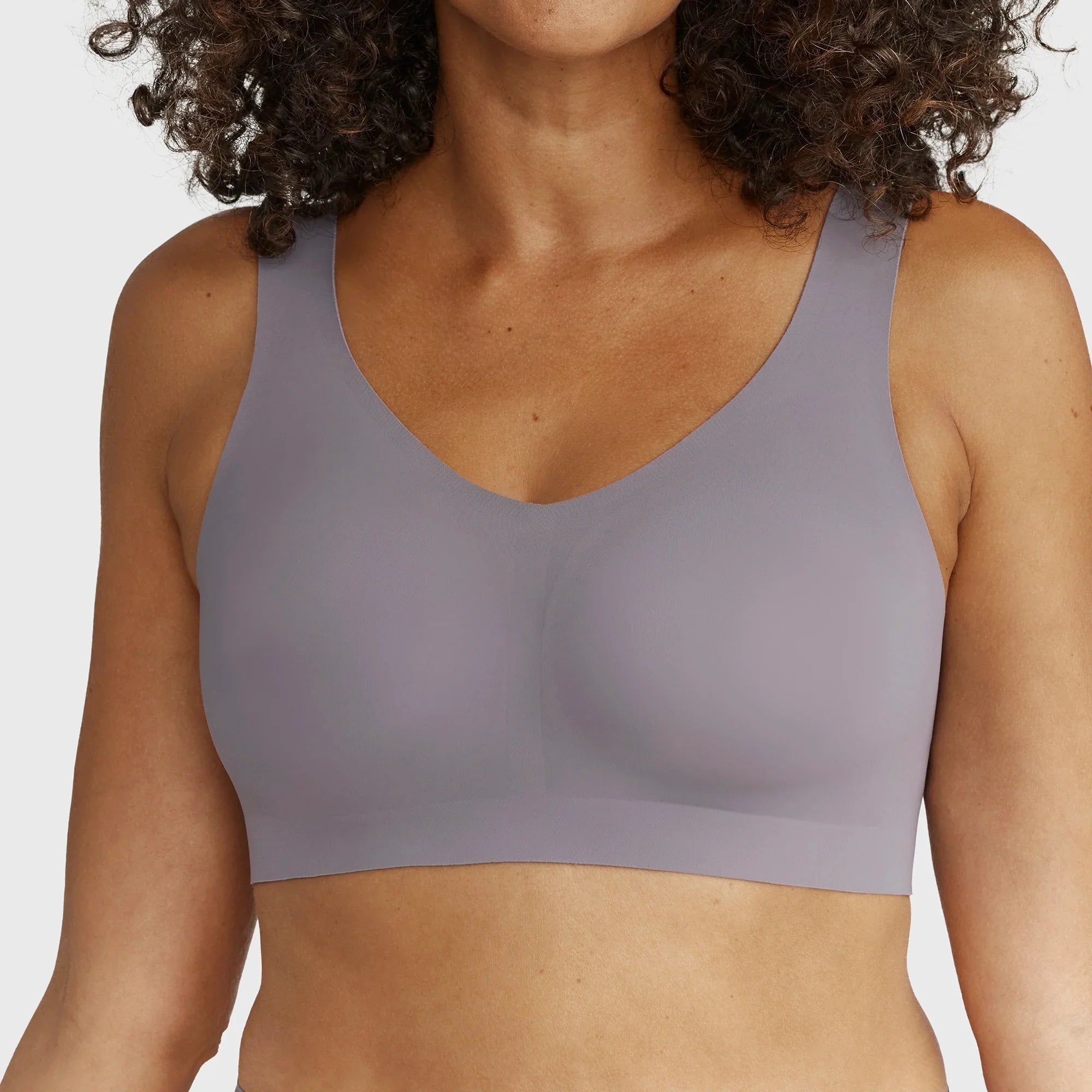 Close up of Woman wearing the Evelyn Bobbie Defy Bra in London Fog, light grey no wire bra, on a white background.