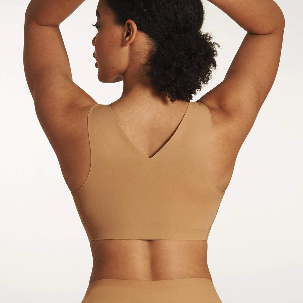 Woman wearing the Evelyn & Bobbie Defy Bra in Mica, light tan no wire pullover bra, against a white background, back view.