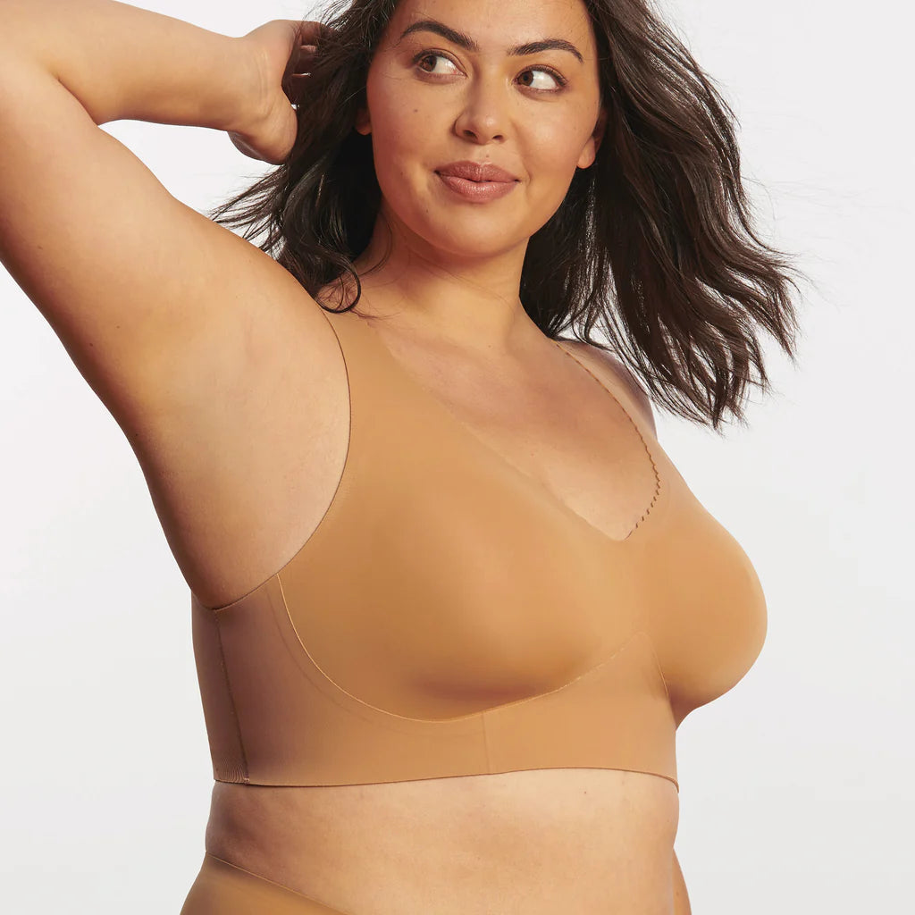 Woman wearing the Evelyn & Bobbie Evelyn Bra in Mica, tan no wire pullover bra, against a white background, front view.