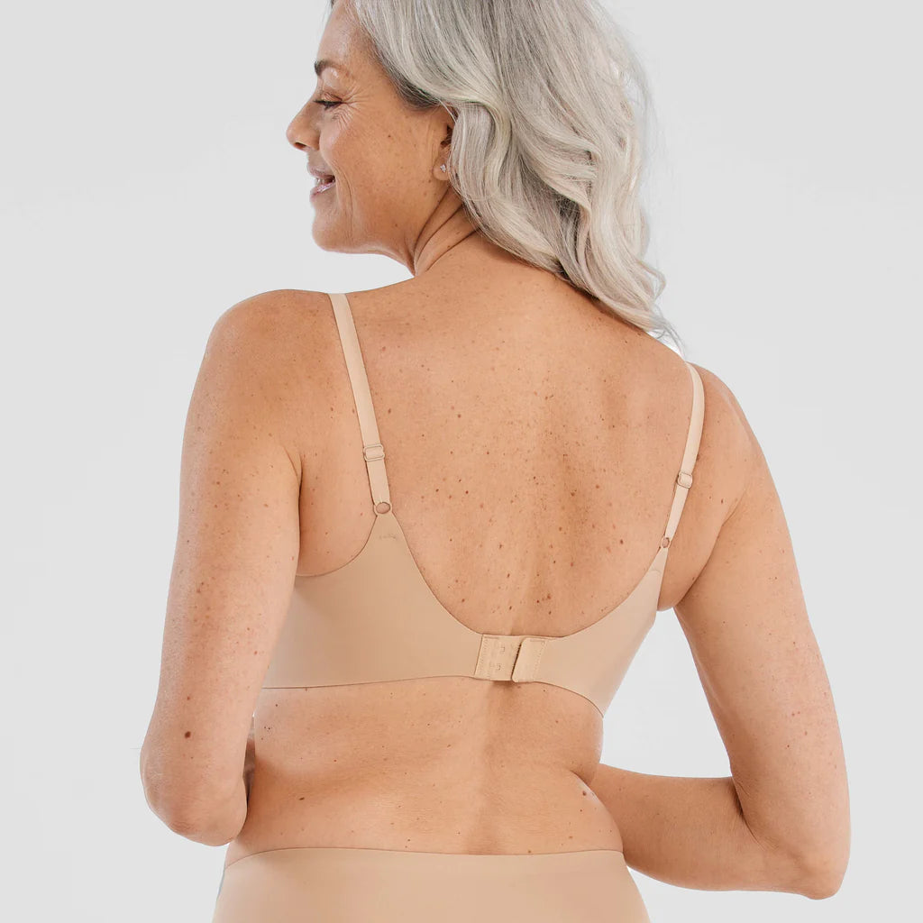 Woman wearing the Evelyn & Bobbie Starlette Bra in Sand, beige no wire bra, against a white background, back view.