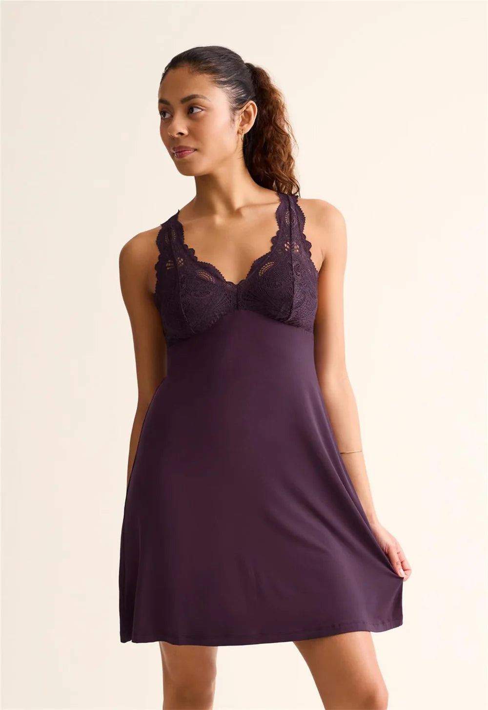 Woman wearing a purple nightgown with lace details on a beige background