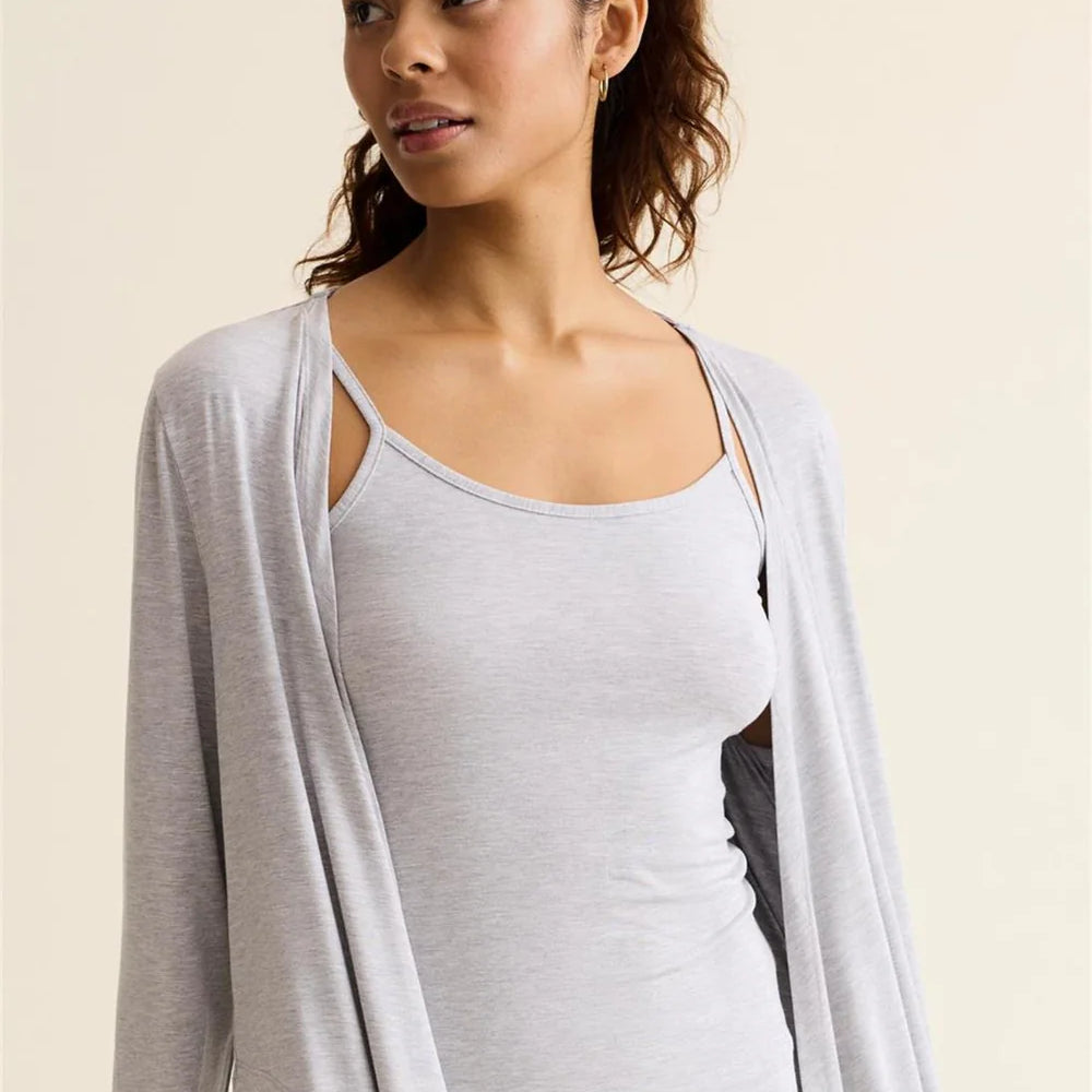Woman wearing a light gray cardigan over a white top against a beige background