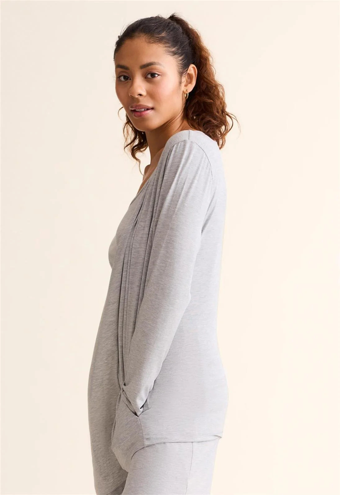Woman wearing a light gray cardigan over a white top on a beige background