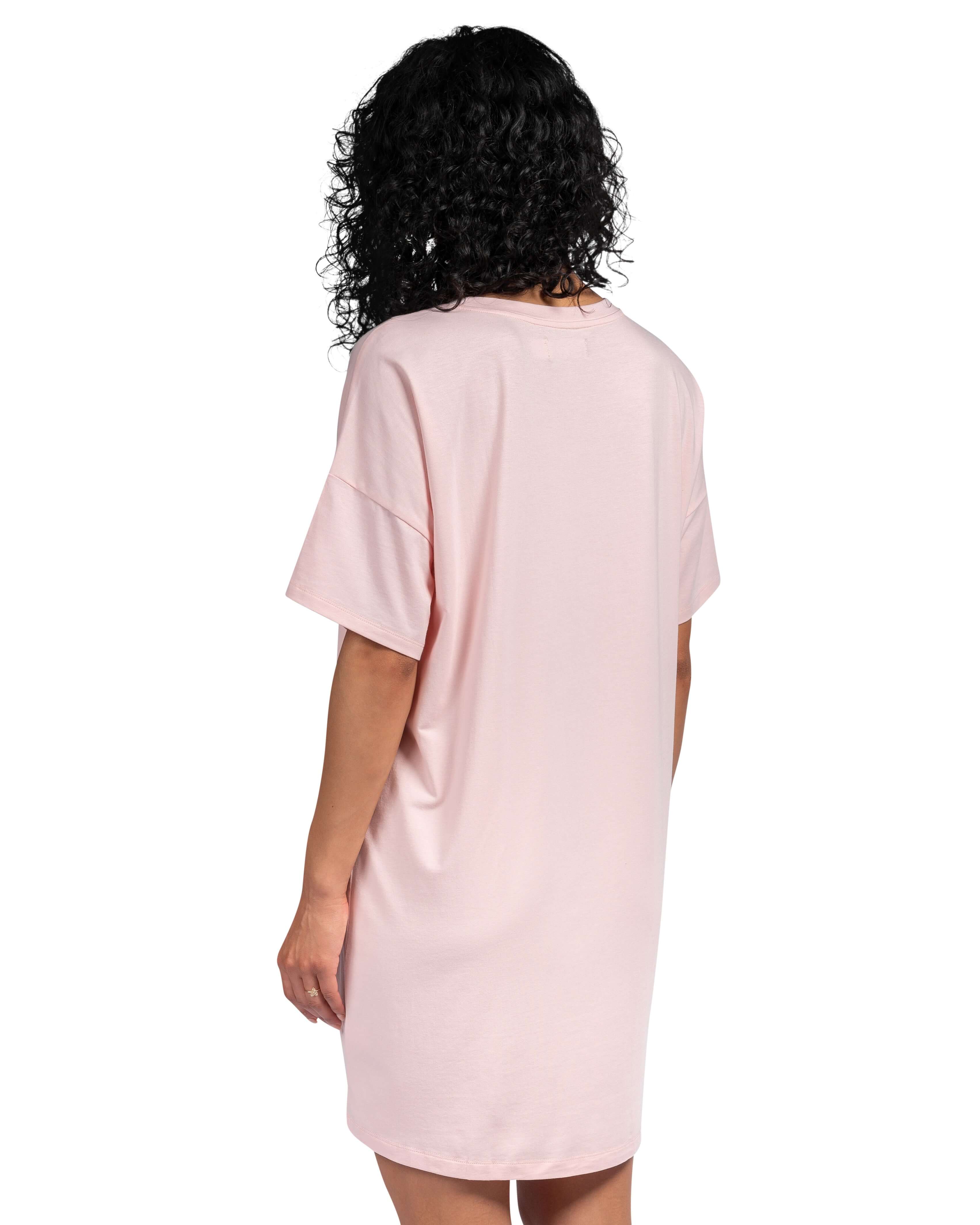 Person wearing a pink t-shirt dress on a white background