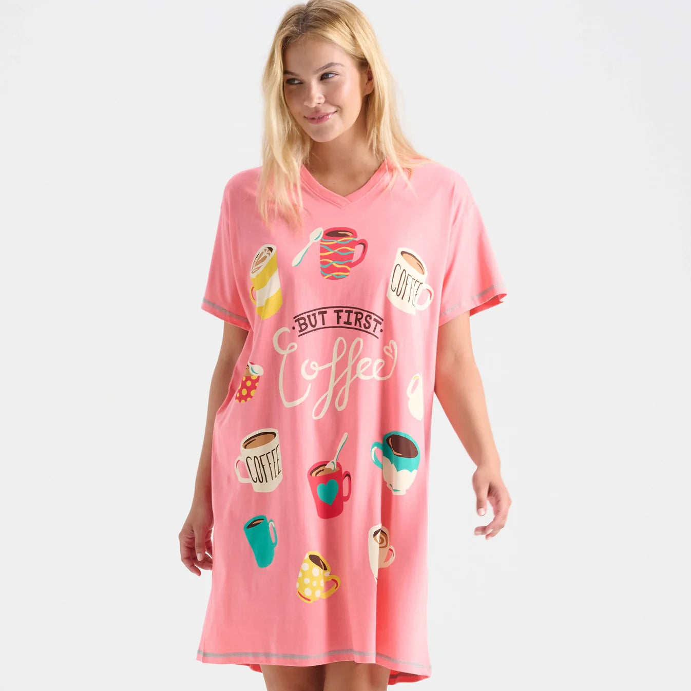 Woman wearing a pink nightshirt with coffee-themed graphics on a white background