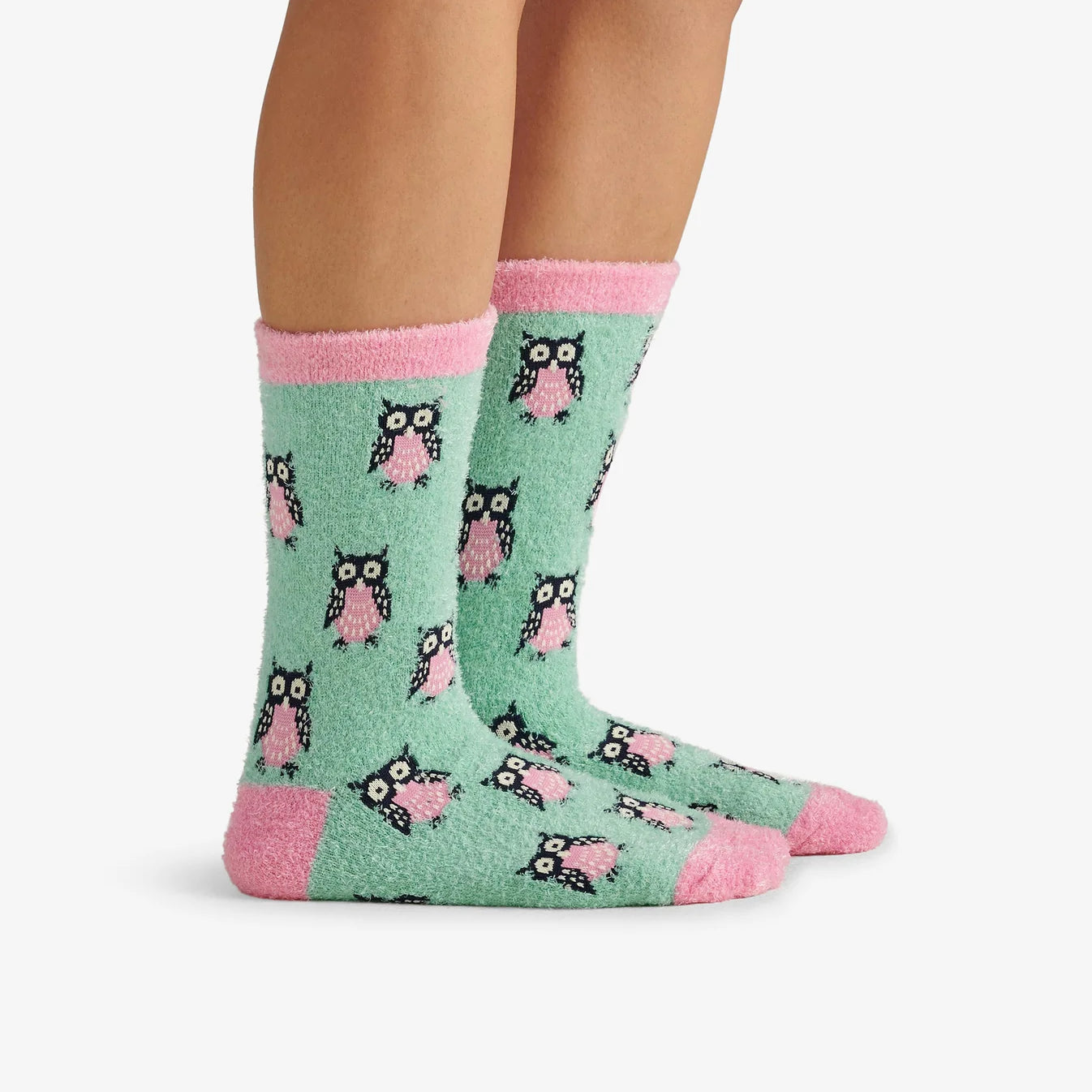 Green socks with owl pattern and pink accents worn by a person on a white background