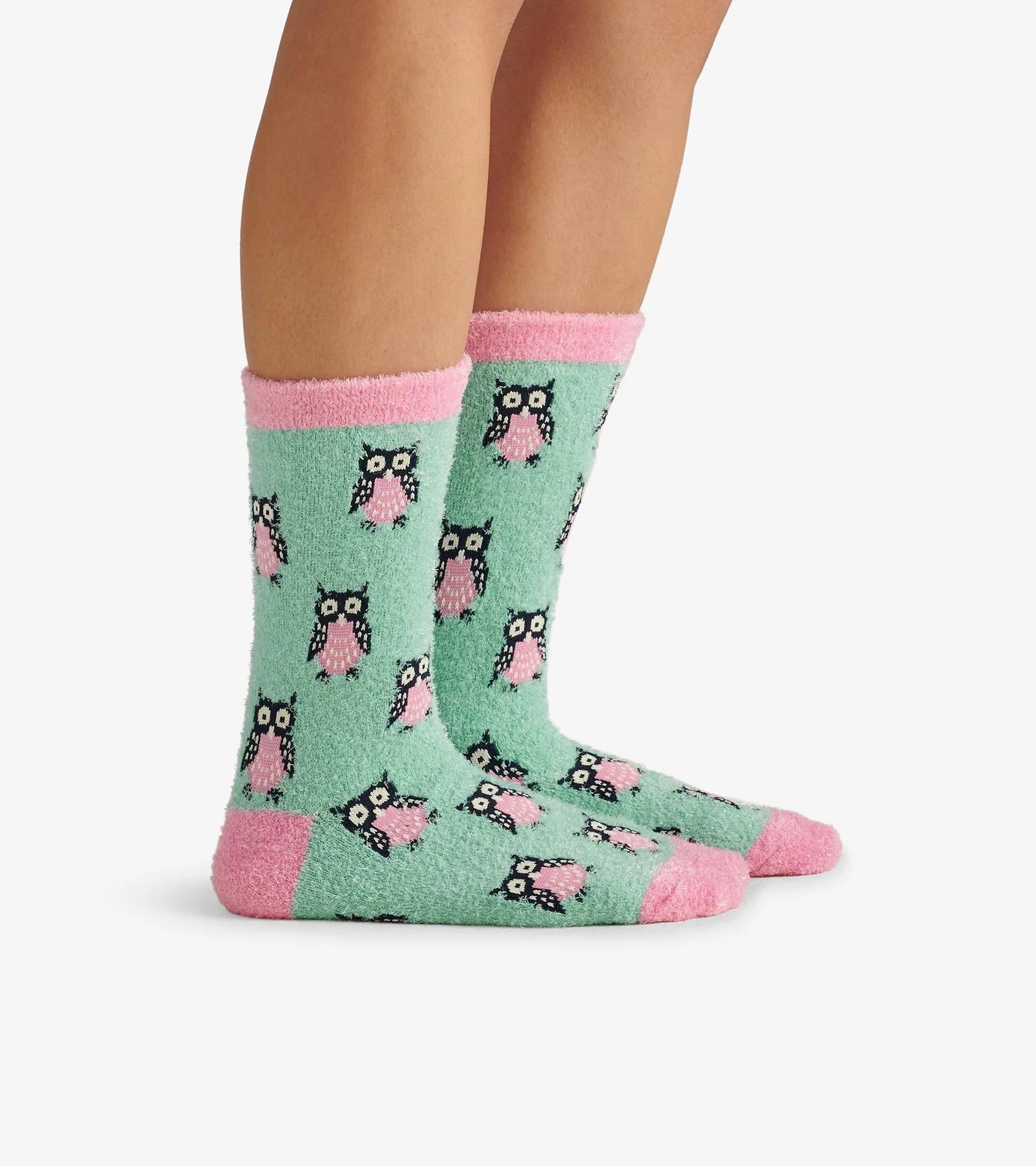 Green socks with owl pattern and pink accents worn by a person on a white background
