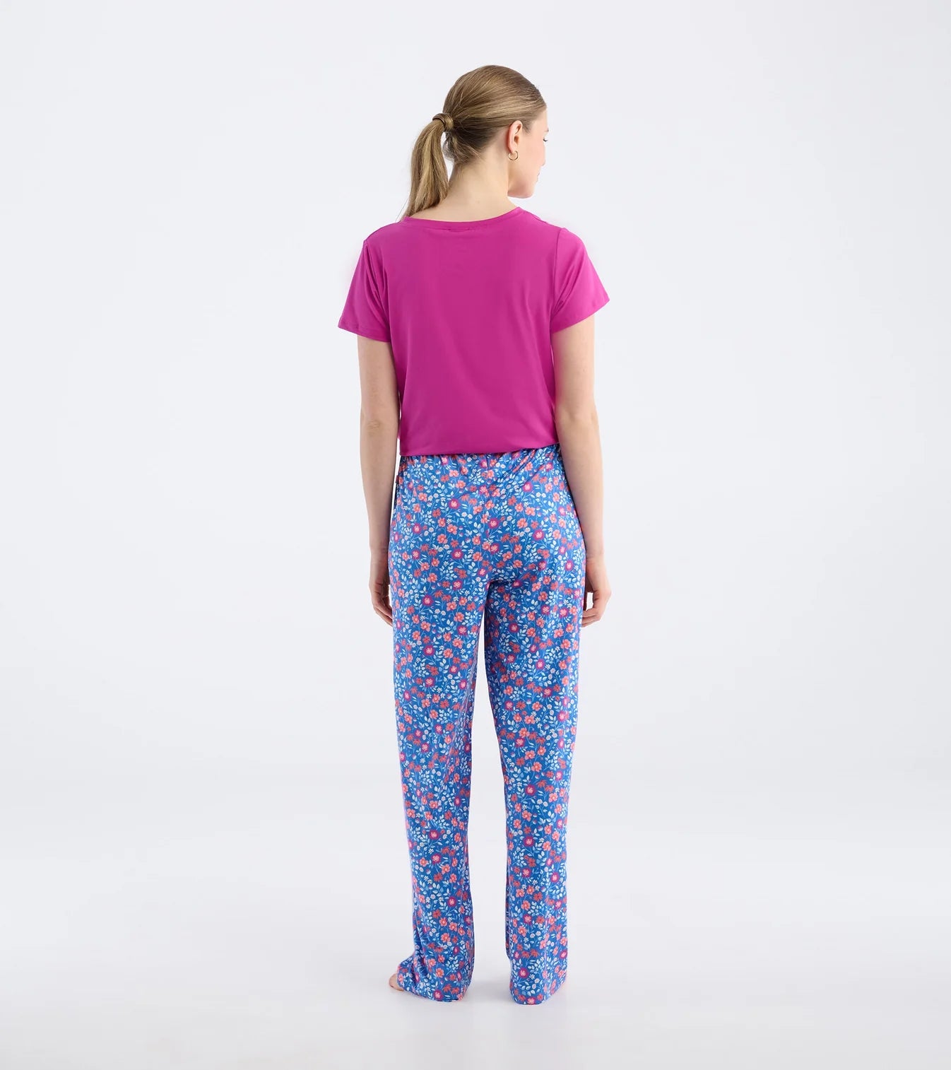 Woman wearing a pink t-shirt and colorful patterned pants on a white background