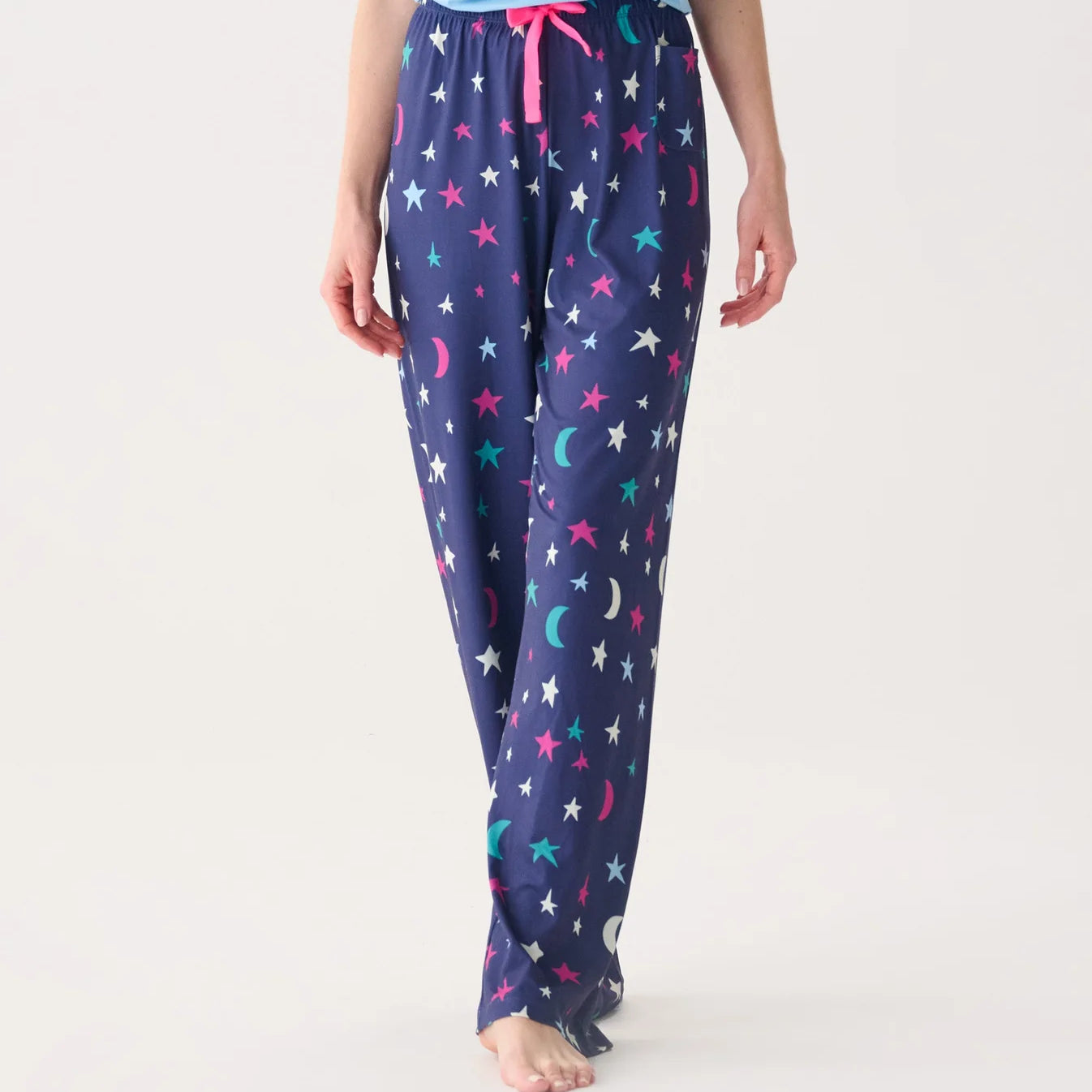 Navy blue pajama pants with star and moon pattern worn by a person on a white background