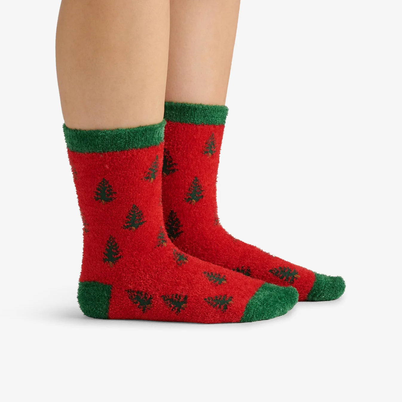 Red socks with green accents and tree patterns worn by a person on a white background