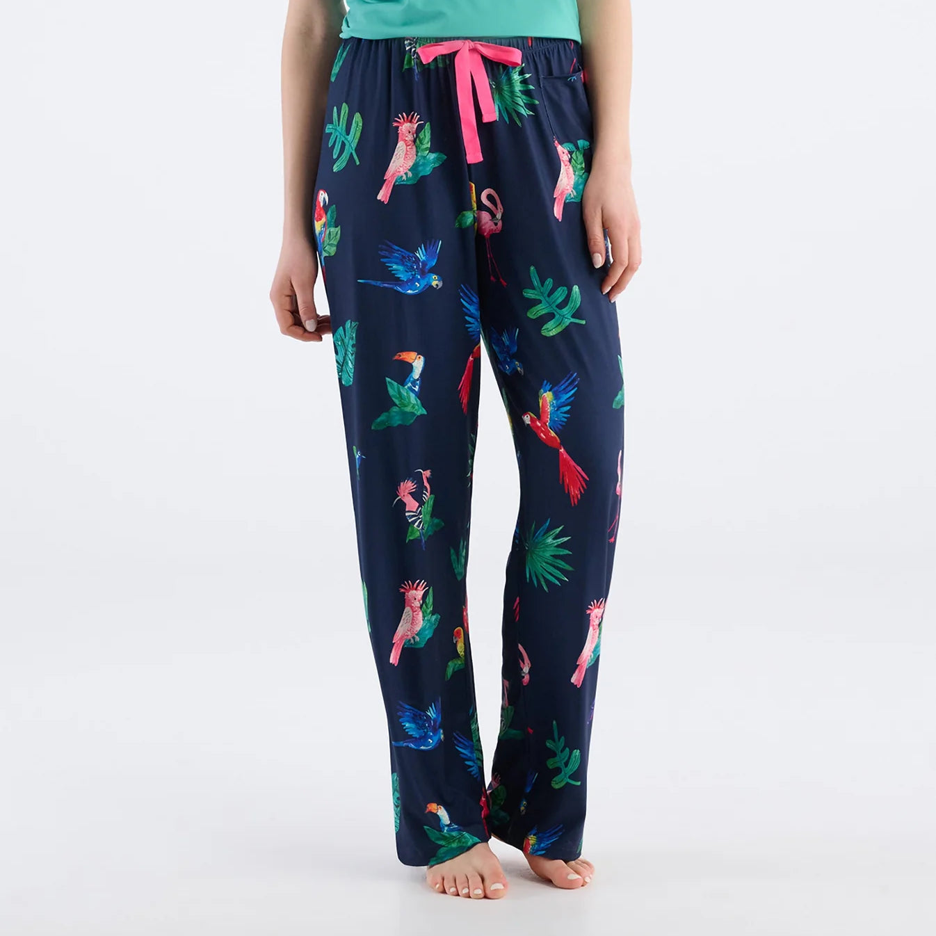 Navy blue pajama pants with colorful parrot pattern worn by a person on a white background