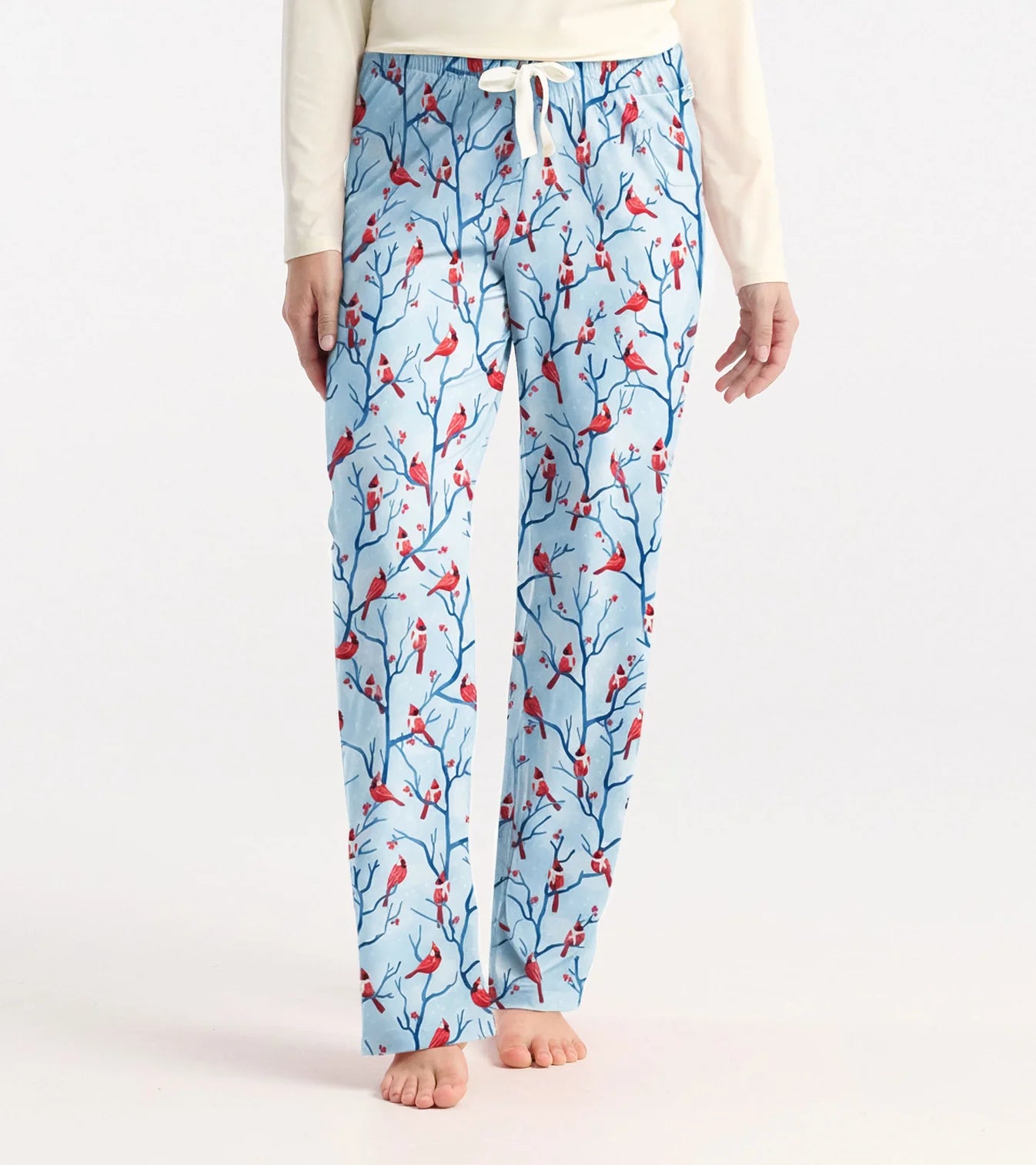 Light blue pajama pants with red bird and branch pattern worn by a person on a white background