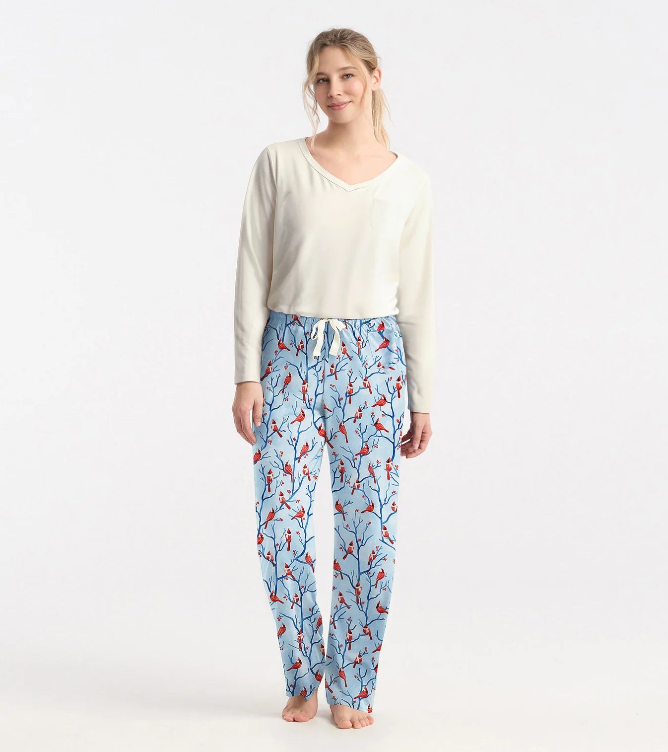 Woman wearing a white top and blue floral pants on a white background