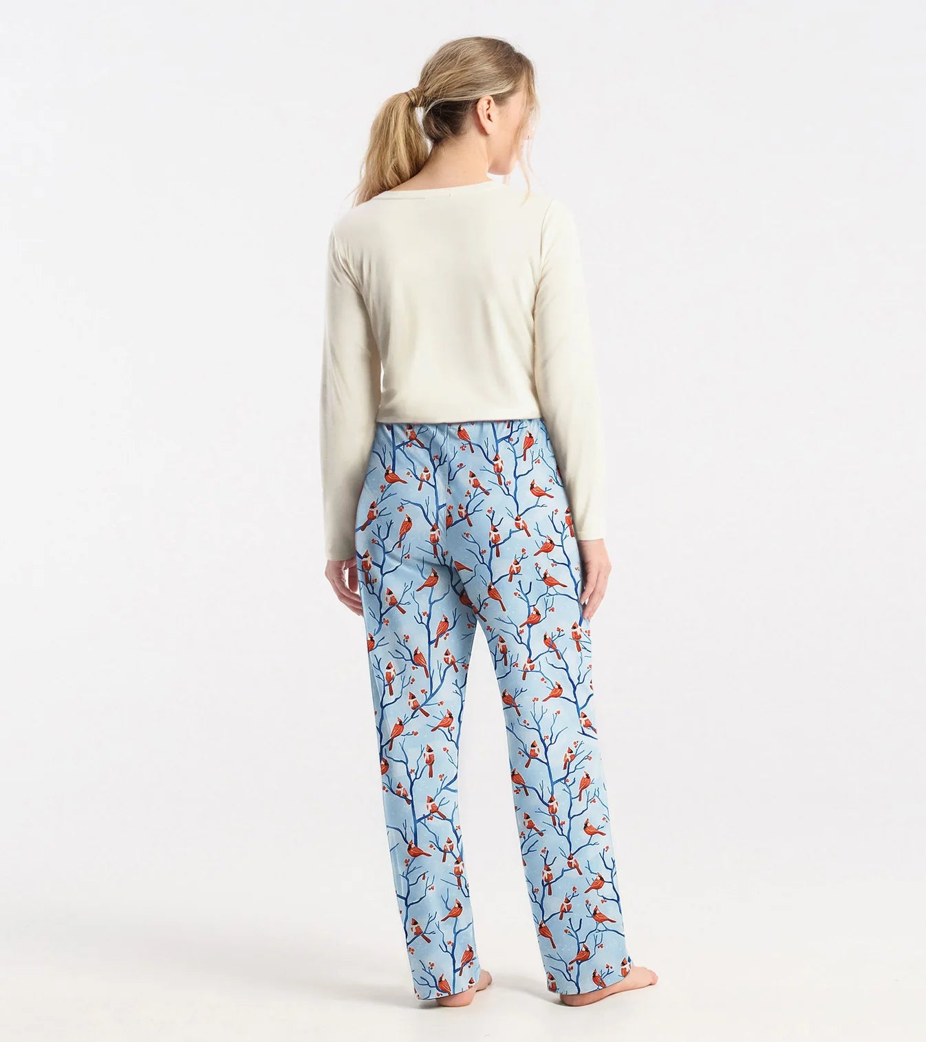 Woman wearing blue pajama pants with bird pattern on a white background