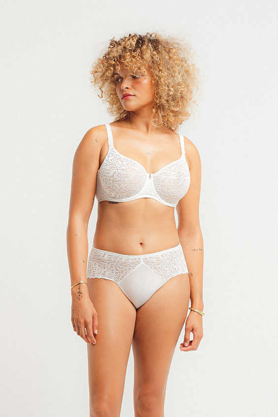 Woman wearing a white lace bra and panties set on a light background