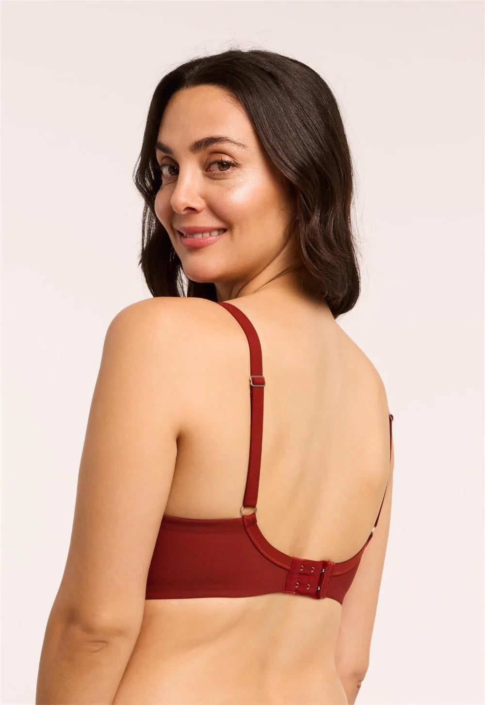 Woman wearing a red bralette against a plain background