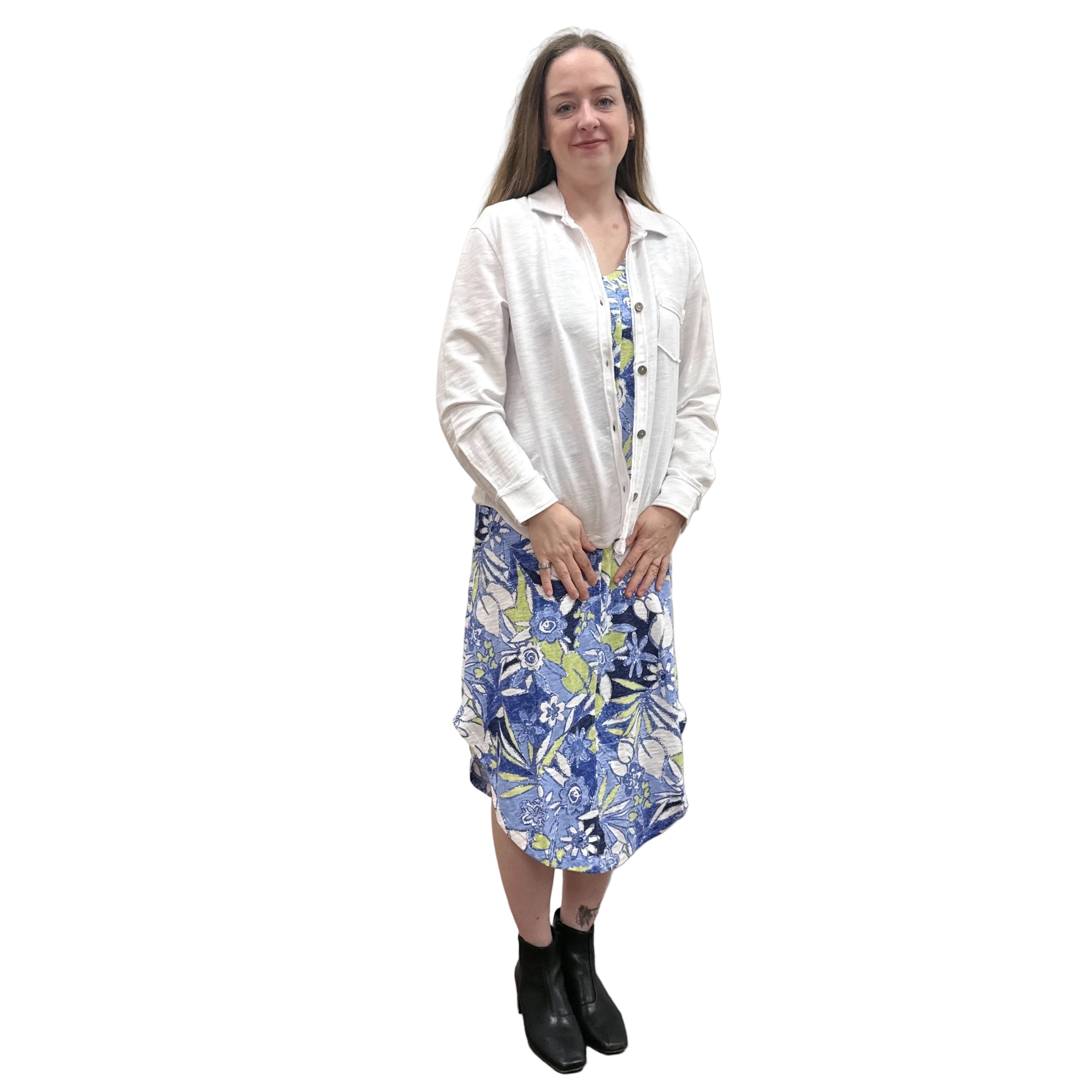 Person wearing a white Papa Anywhere Shacket shirt and blue floral dress standing against a plain wall.