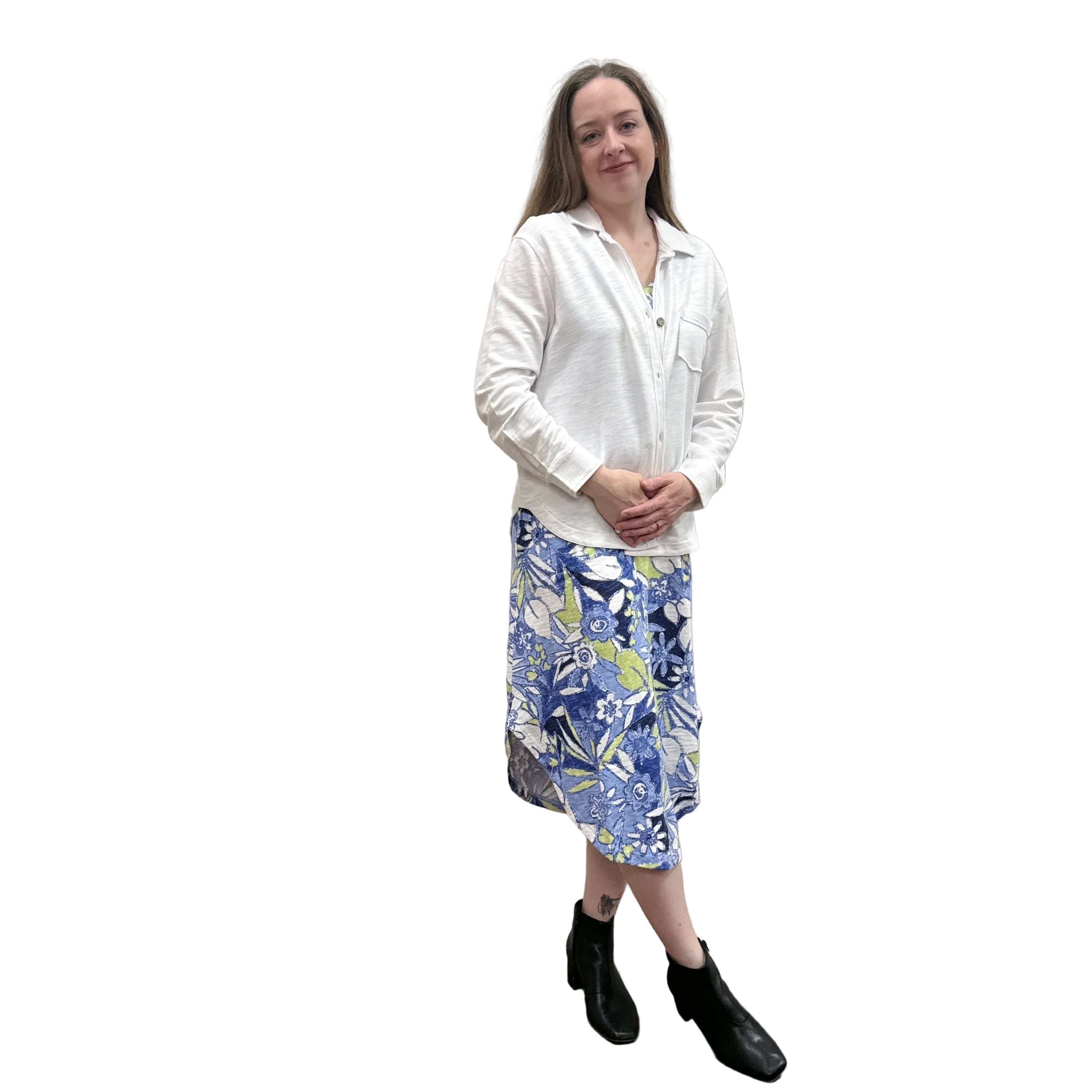 Person wearing a white Papa Anywhere Shacket shirt and blue floral dress standing against a plain wall.