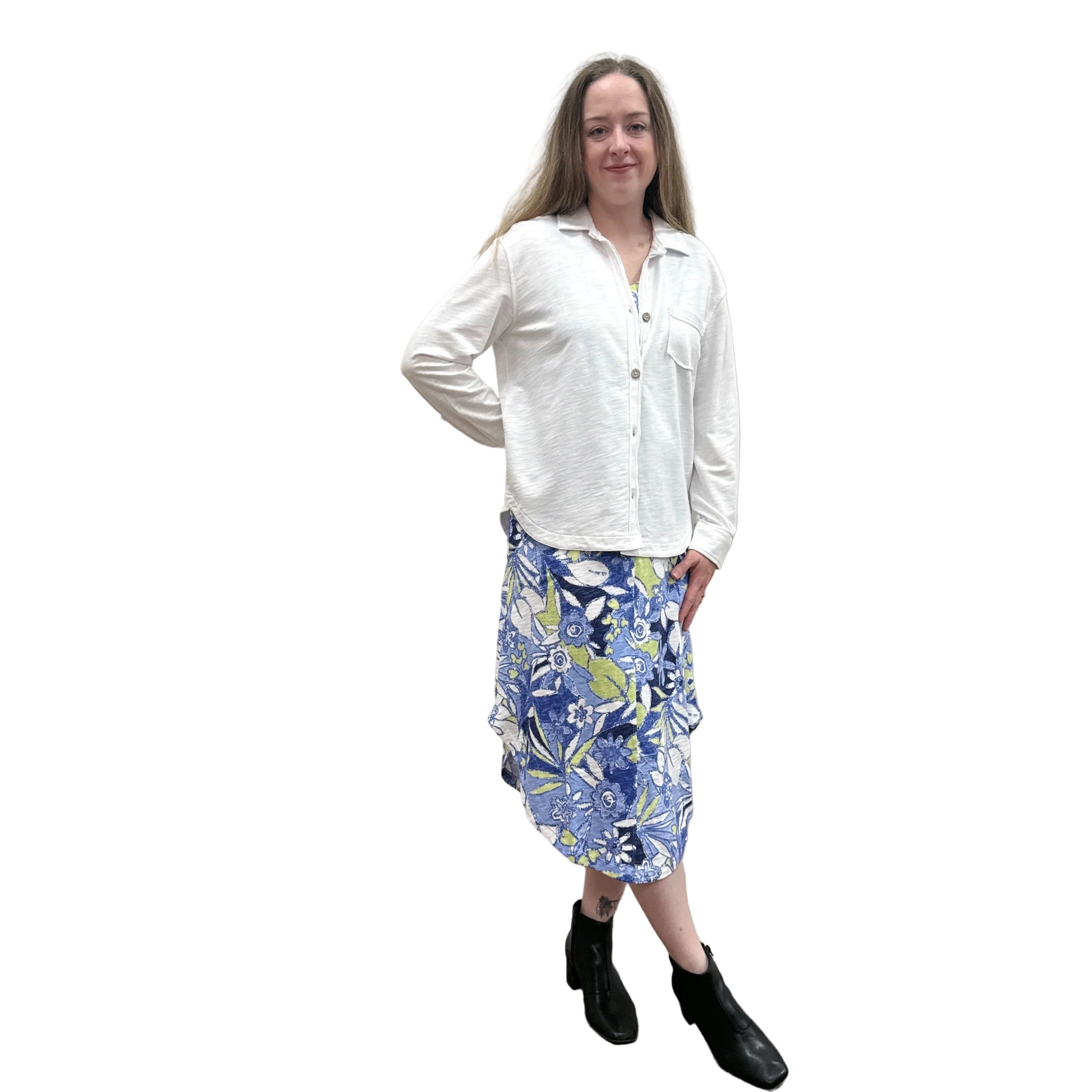Person wearing a white Papa Anywhere Shacket shirt and blue floral dress standing against a plain wall.