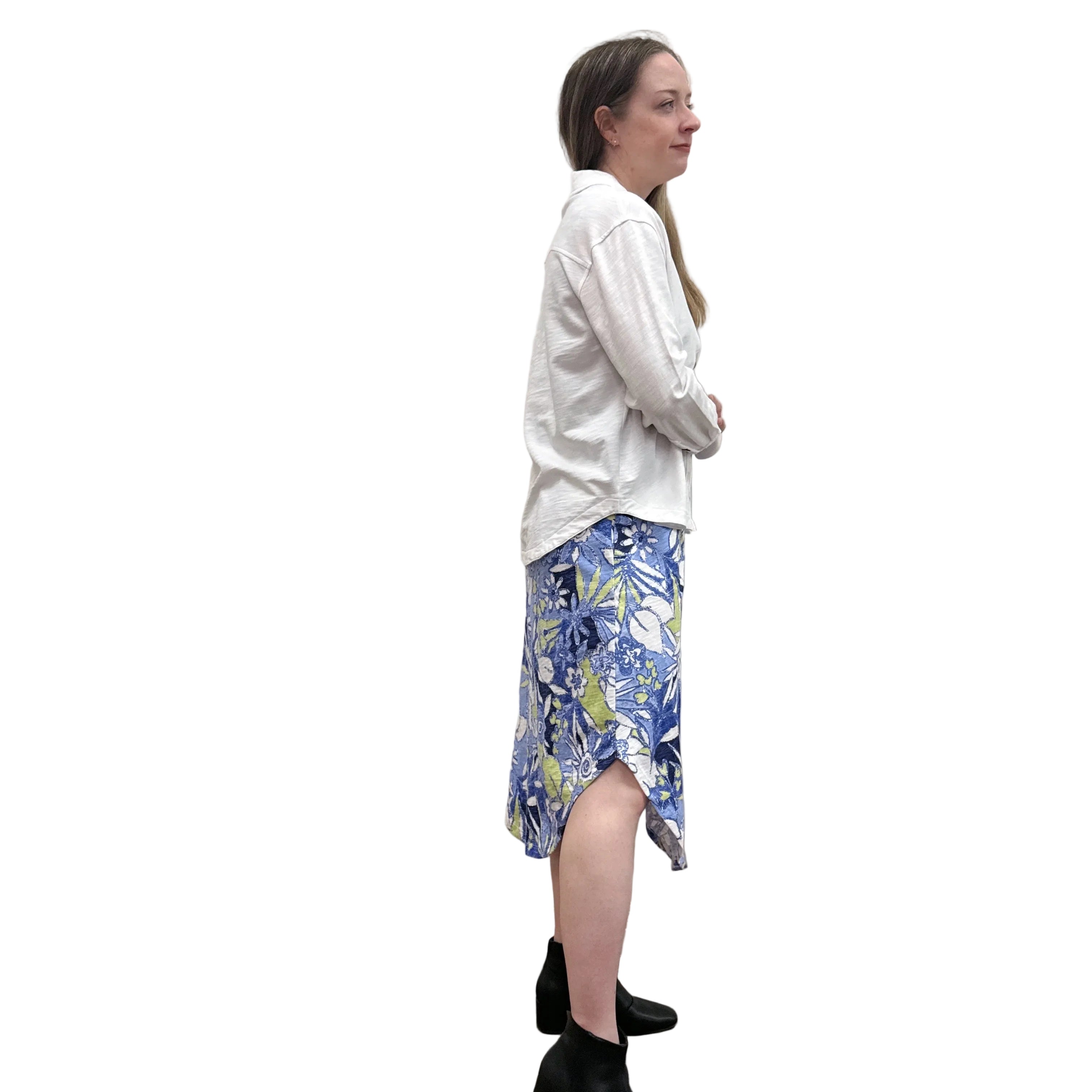 Person wearing a white Papa Anywhere Shacket shirt and blue floral dress standing against a plain wall.